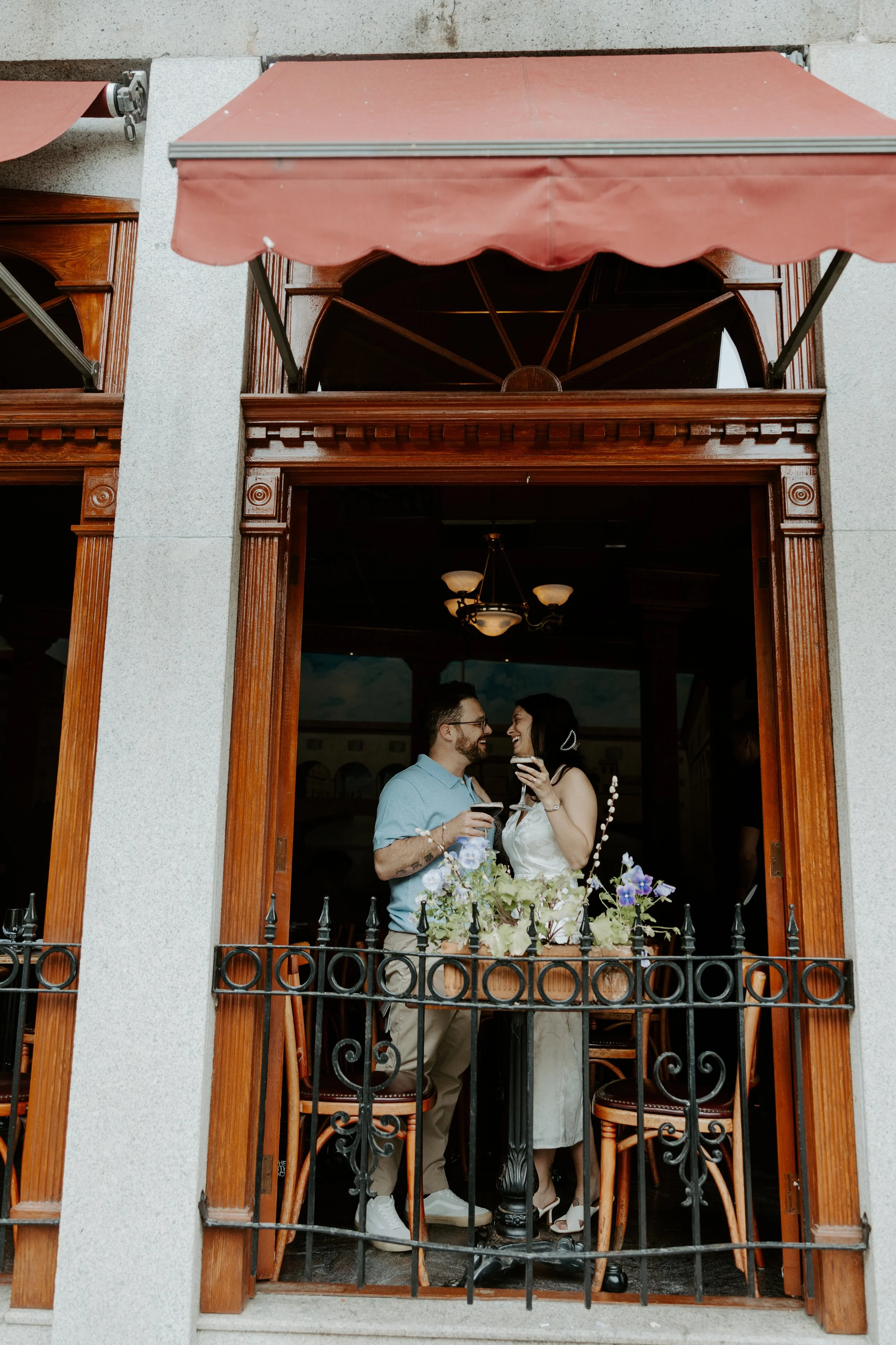 A couple drinking espresso martinis in a cafe, taken by a Boston engagement photographer from outside of the cafe