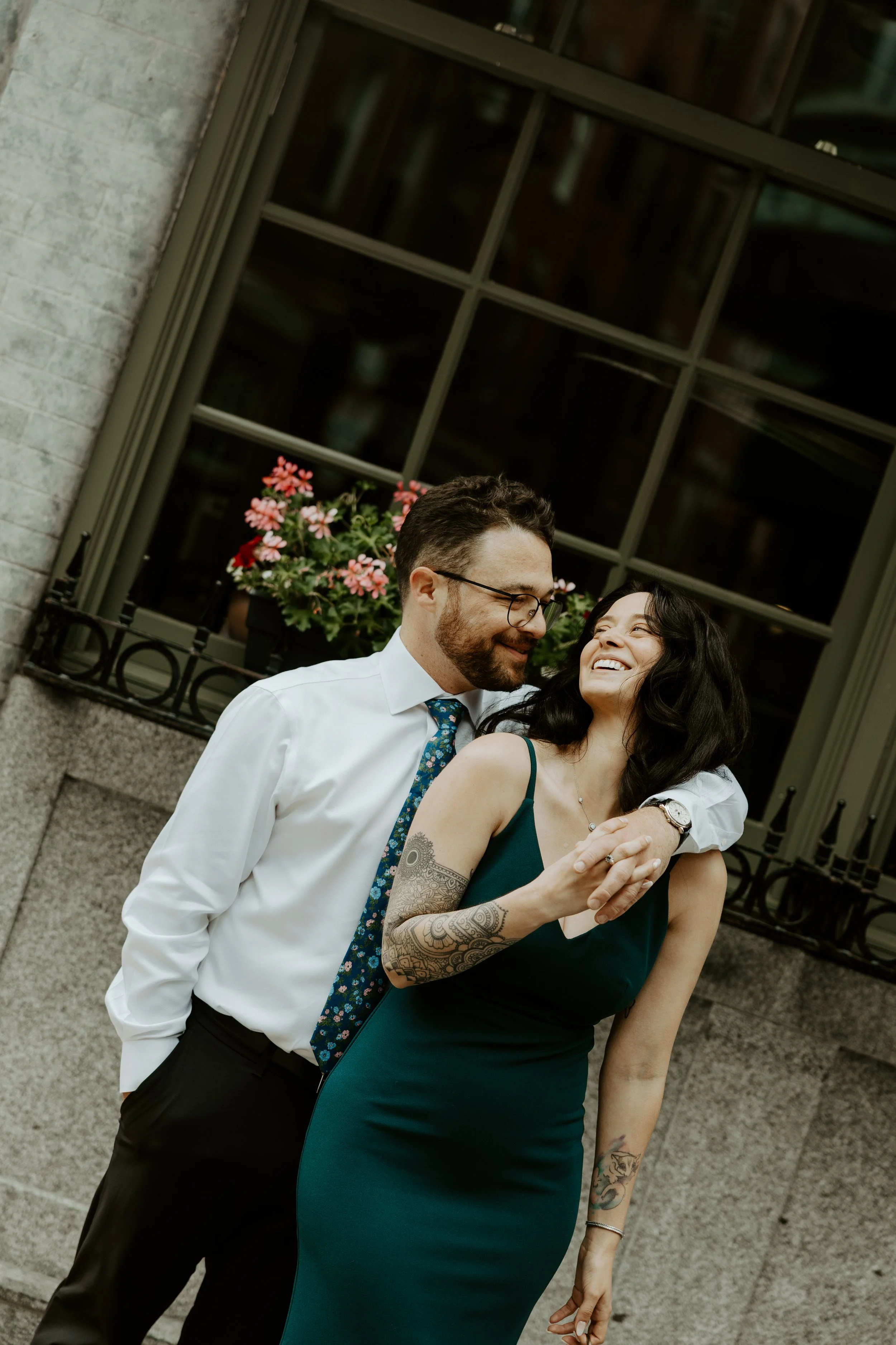 A couple posing for their engagement photoshoot in front of a window