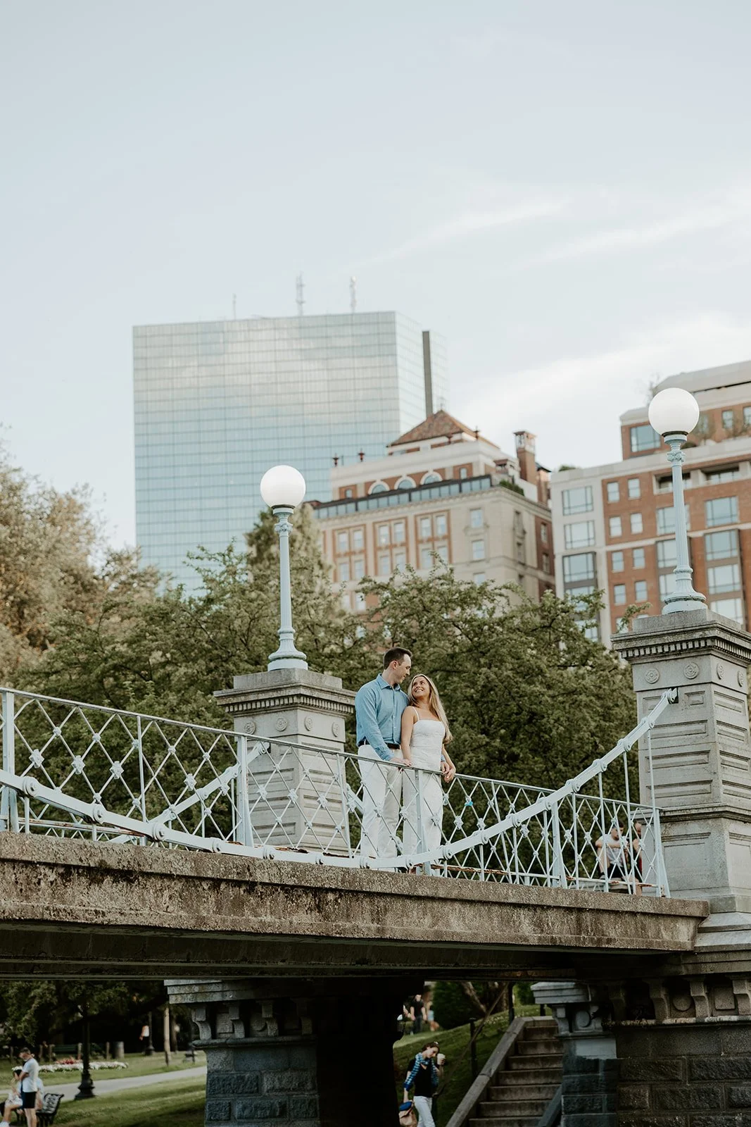 A couple's photo taken by a Boston engagement photographer of them on a bridge at Public Garden