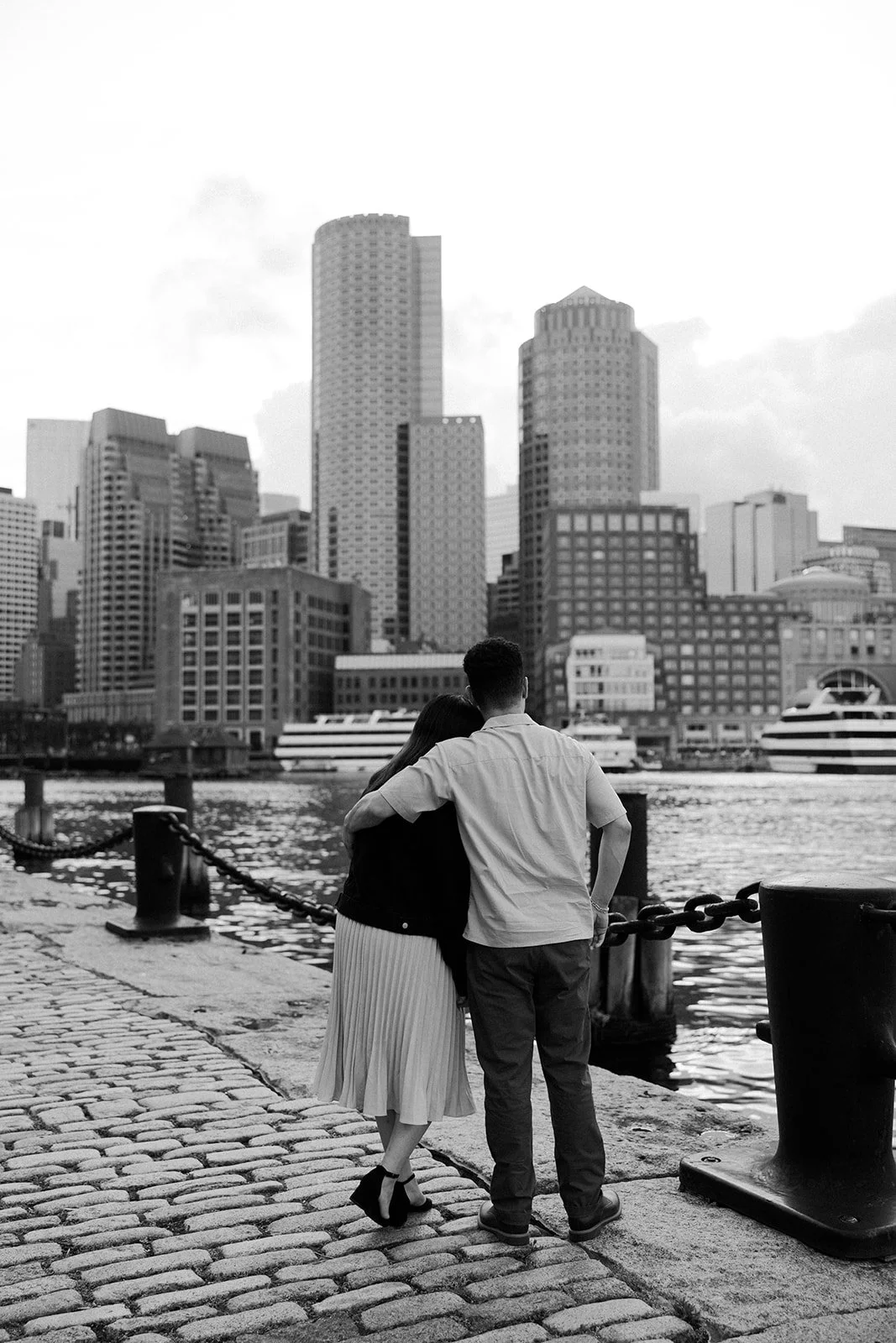 A black and white photo of a couple looking at the Boston skyline