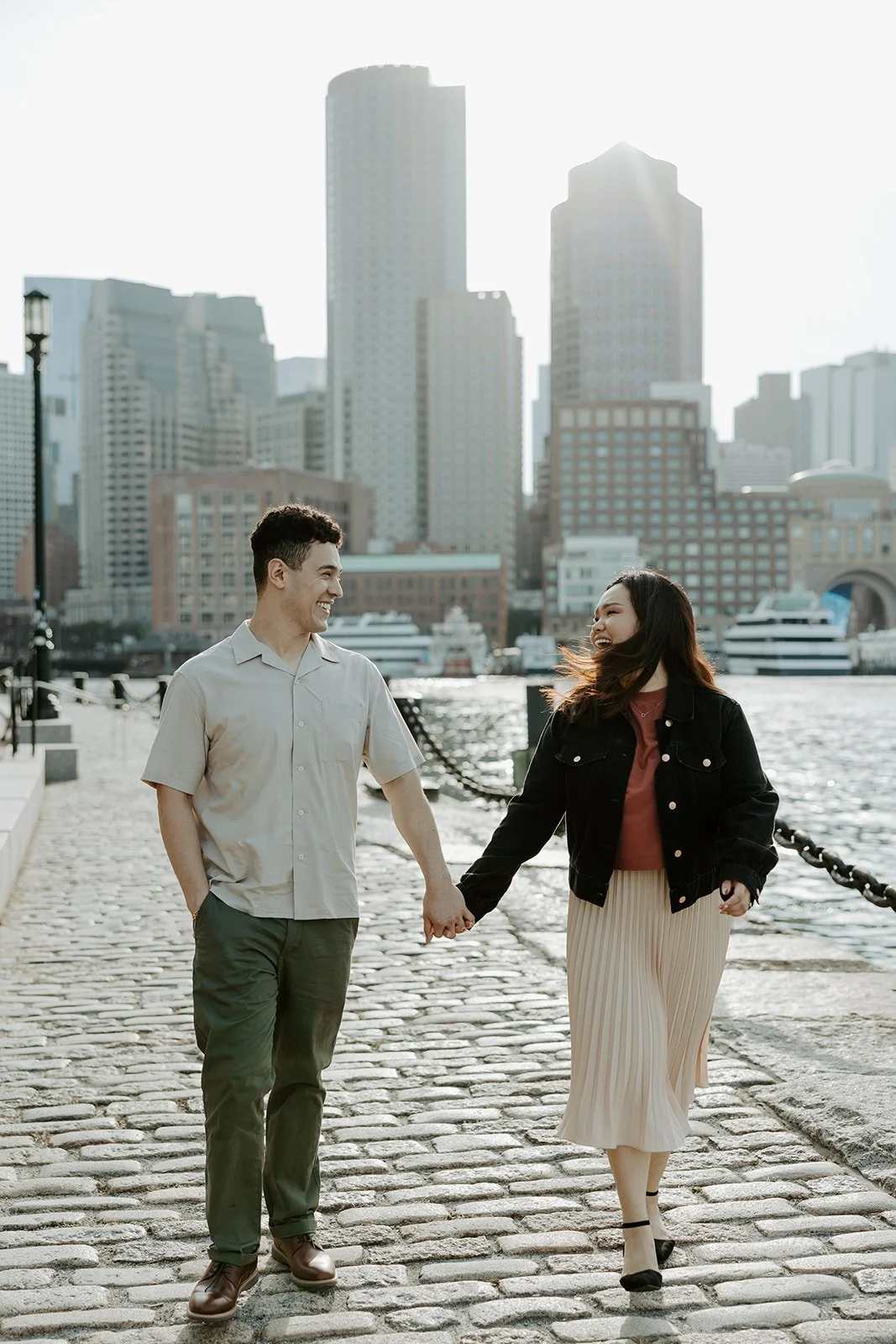 A couple walking along the path at Fan Pier PArk for their engagement photoshoot