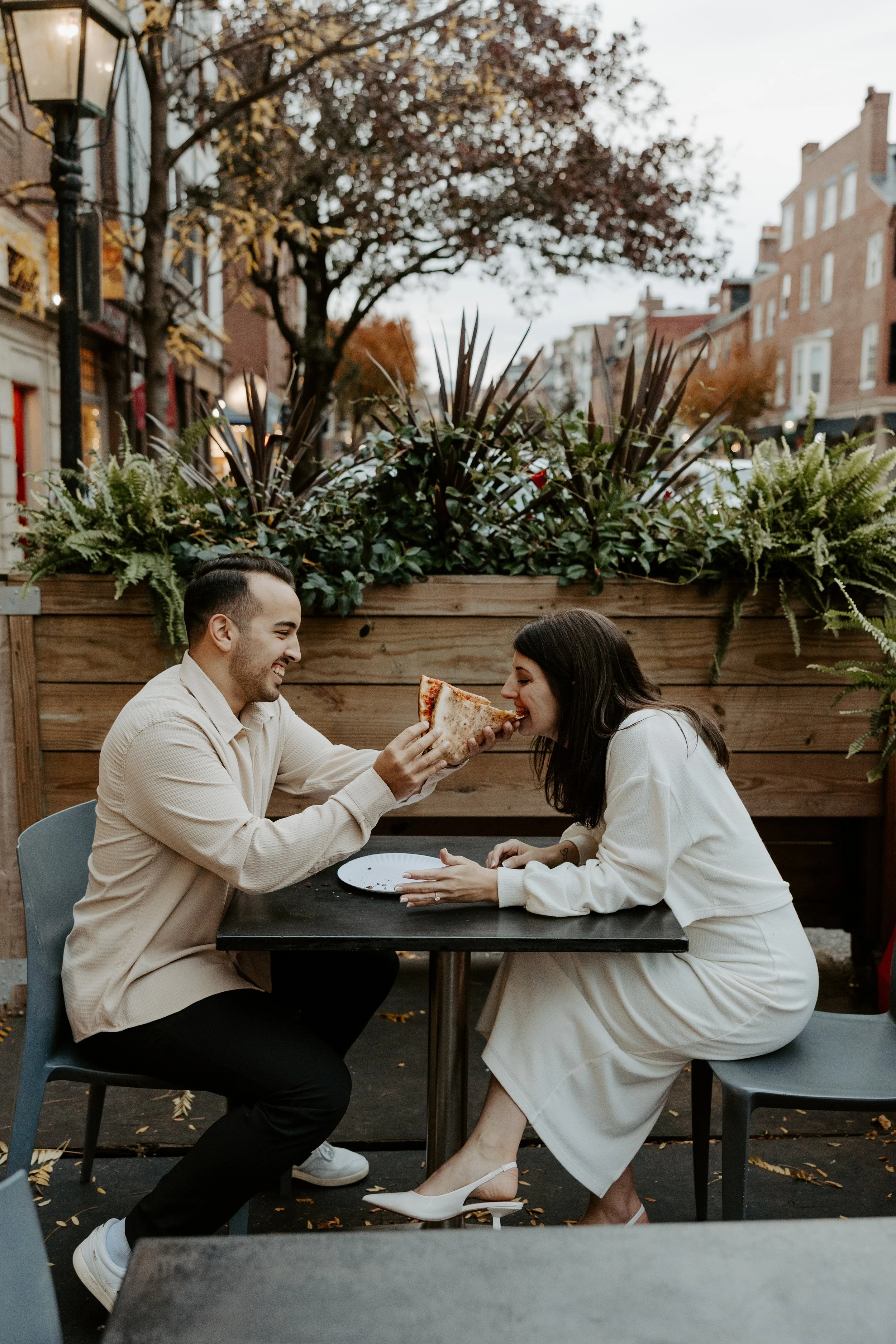 A man feeding his fiancee pizza at their first date spot