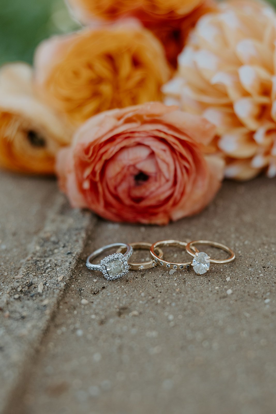 Two bride's wedding rings in front of bouquets from their whimsical wedding