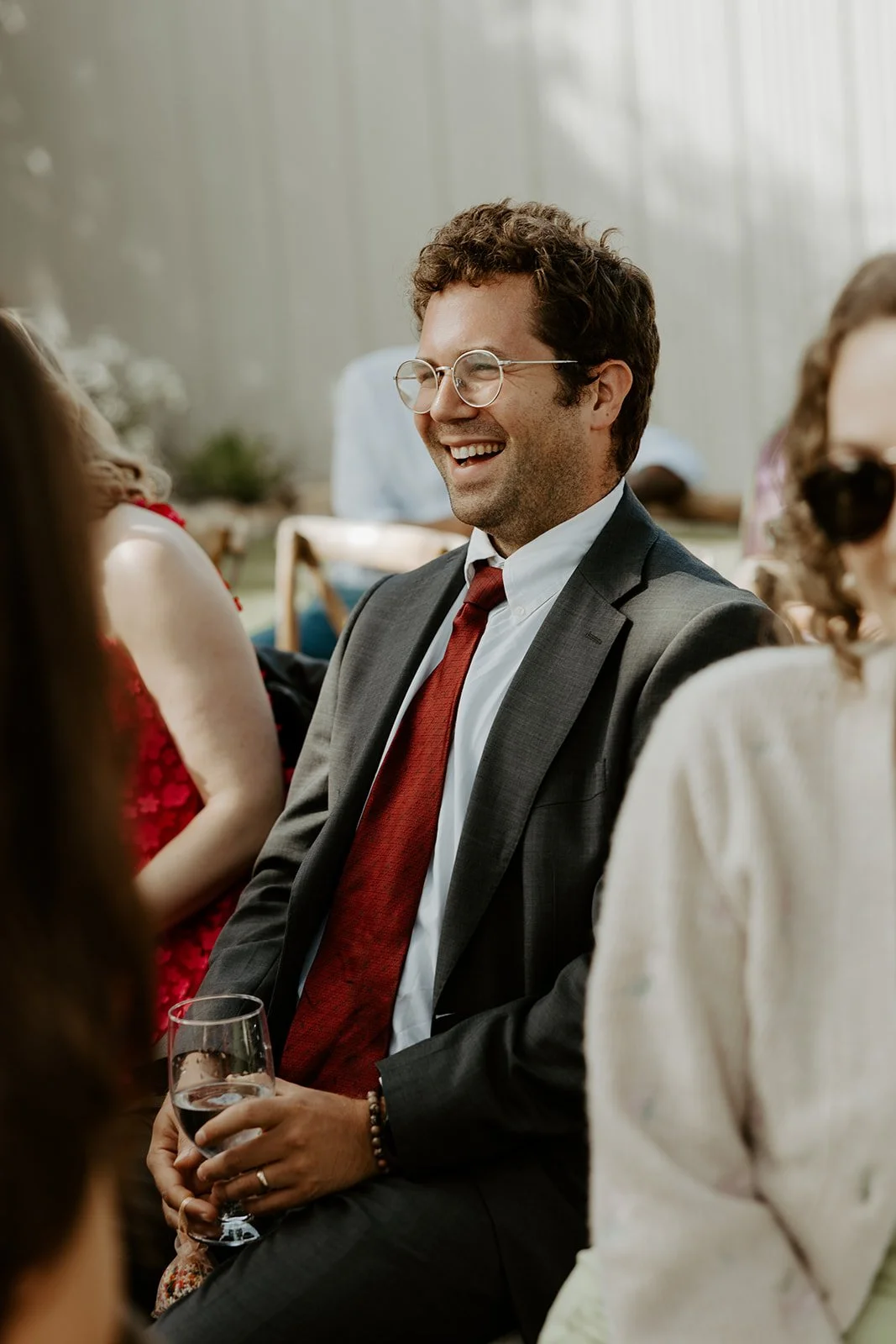 Man laughing while watching a wedding ceremony, captured through documentary style wedding photography