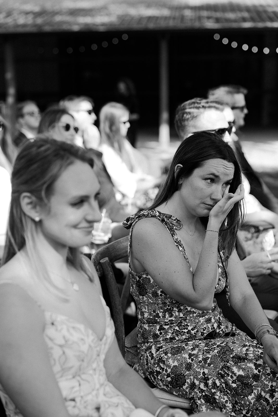A candid wedding photo of a woman crying while watching a wedding ceremony