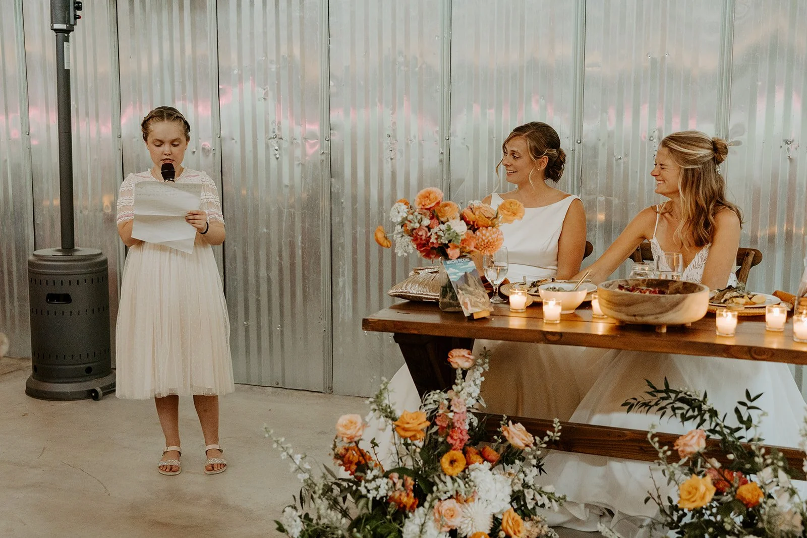 The flower girl giving a speech at a whimsical wedding reception
