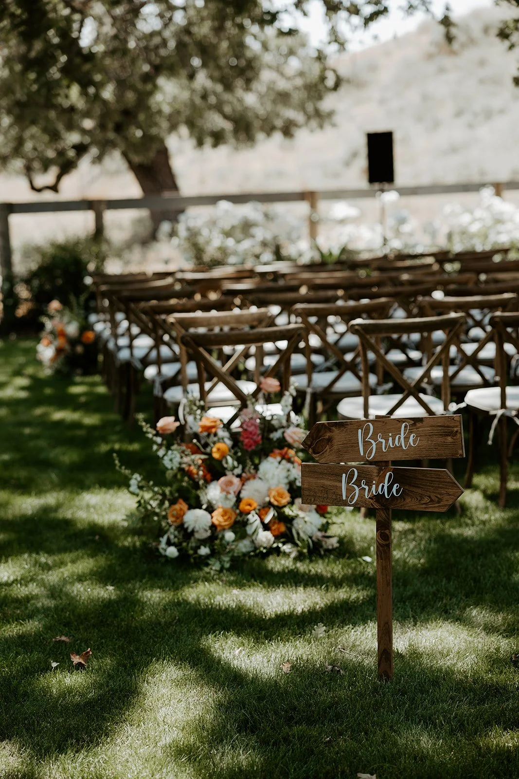 A wedding ceremony setup for a whimsical wedding with signs reading "bride" and "bride"