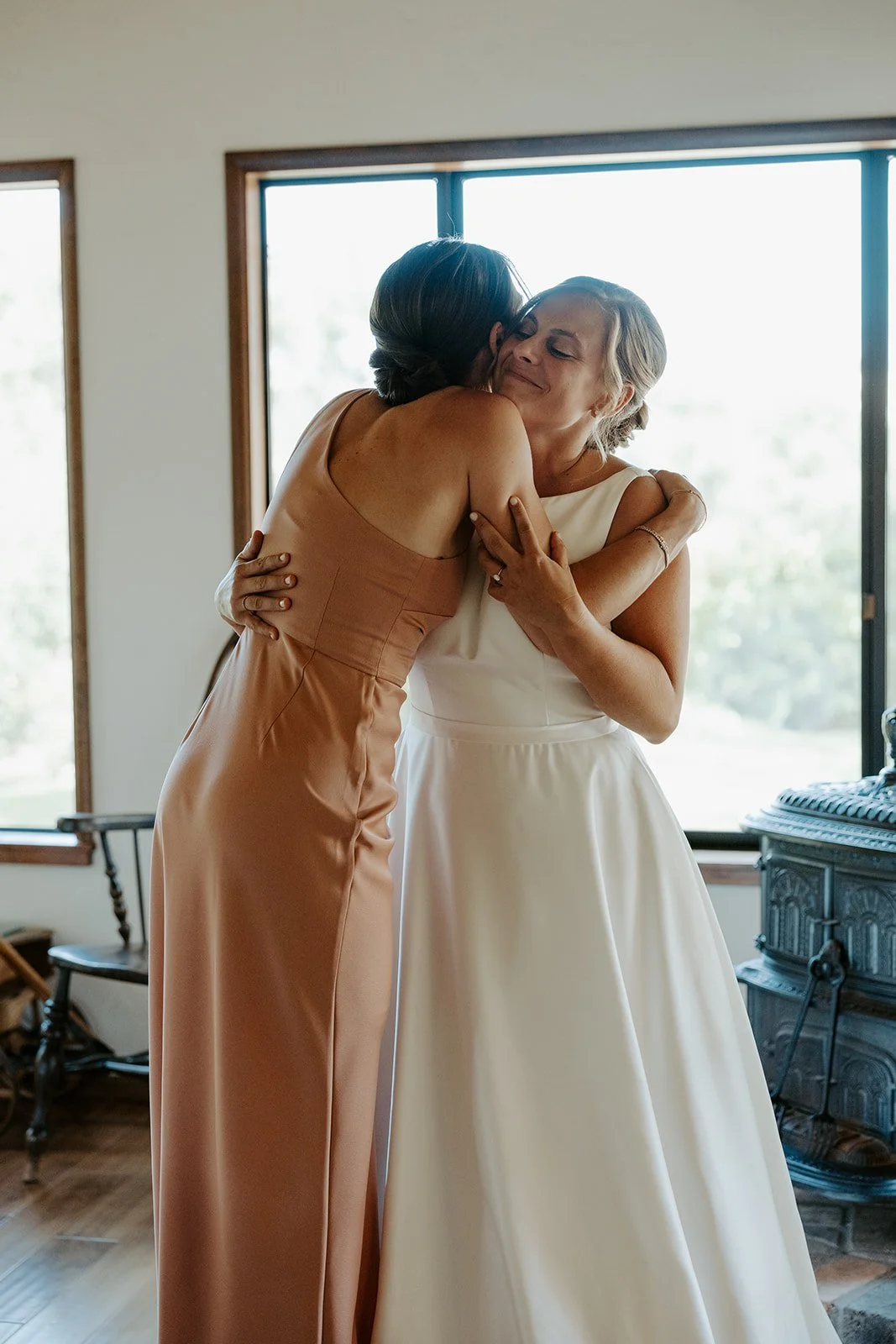 A bride hugging a bridesmaid in documentary style wedding photography