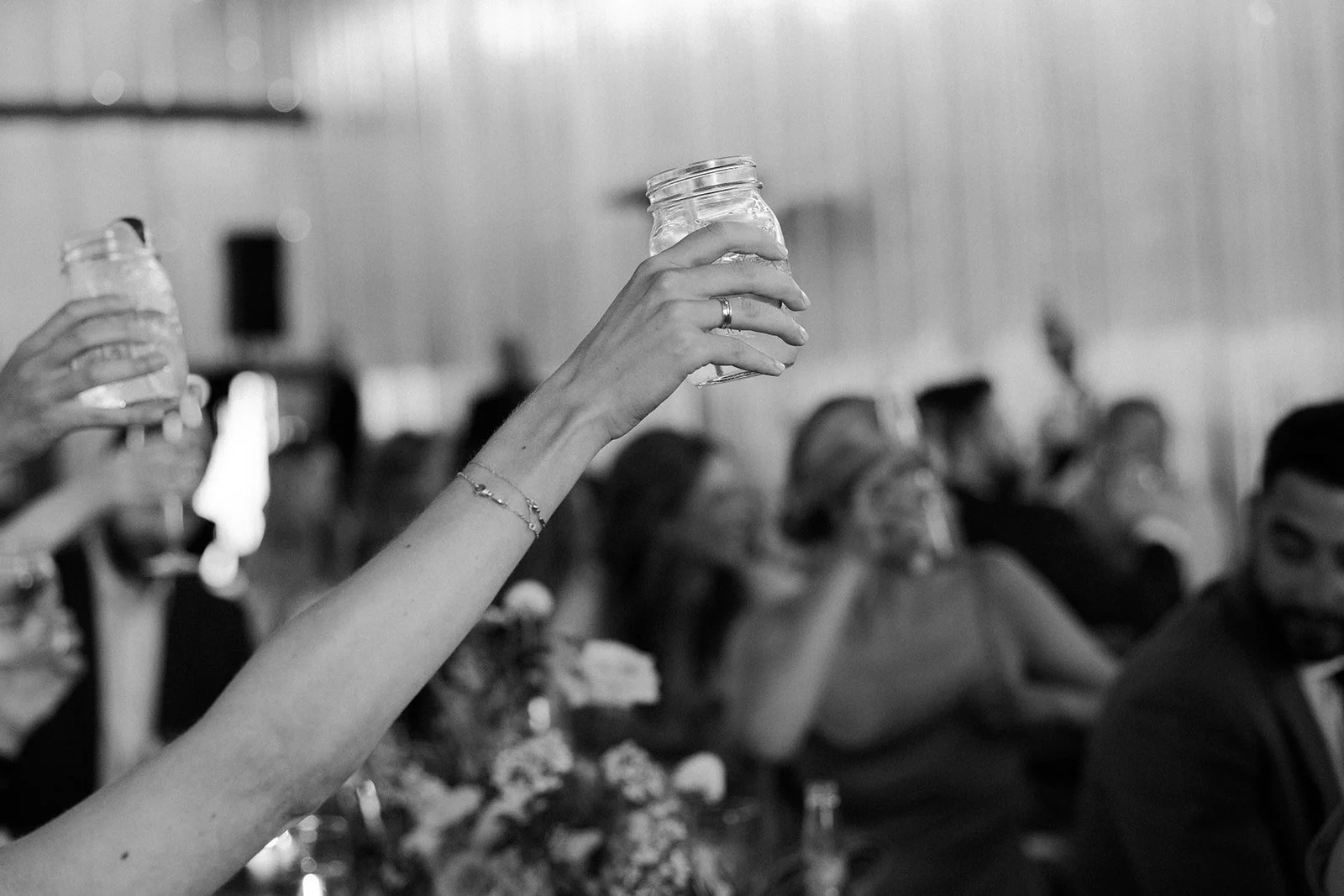 Guests raising mason glasses for toasts at a whimsical wedding