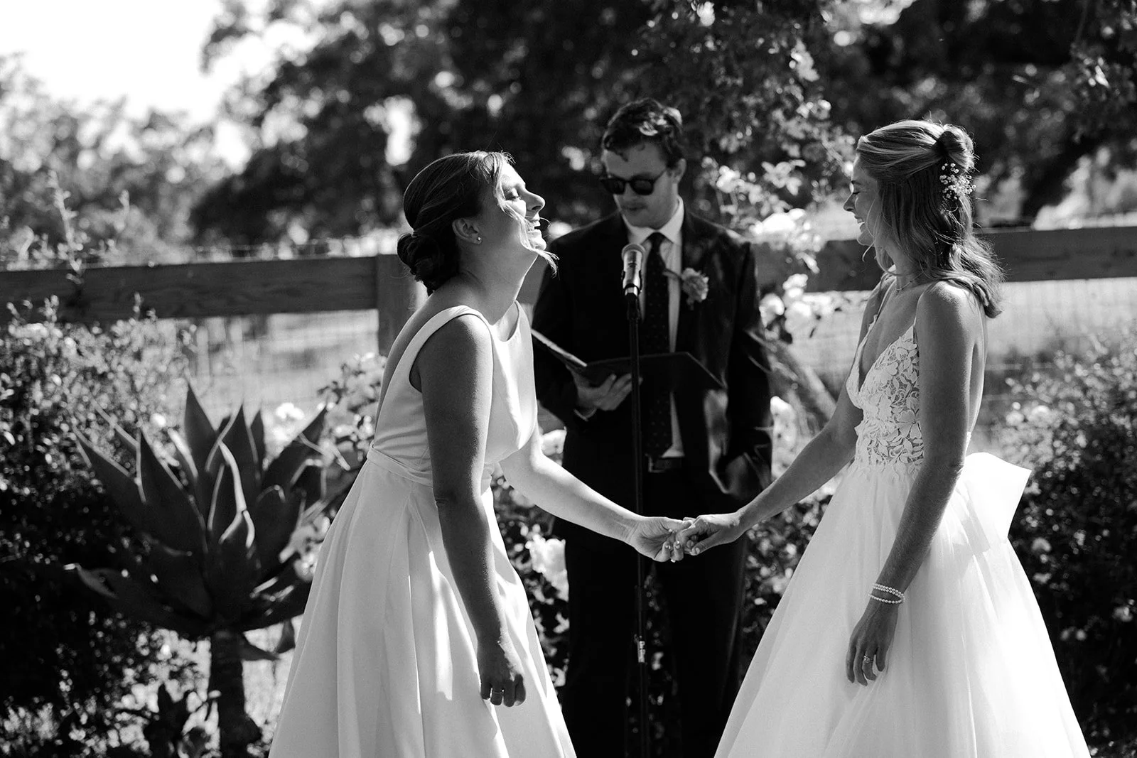 Two brides laughing during their whimsical wedding ceremony