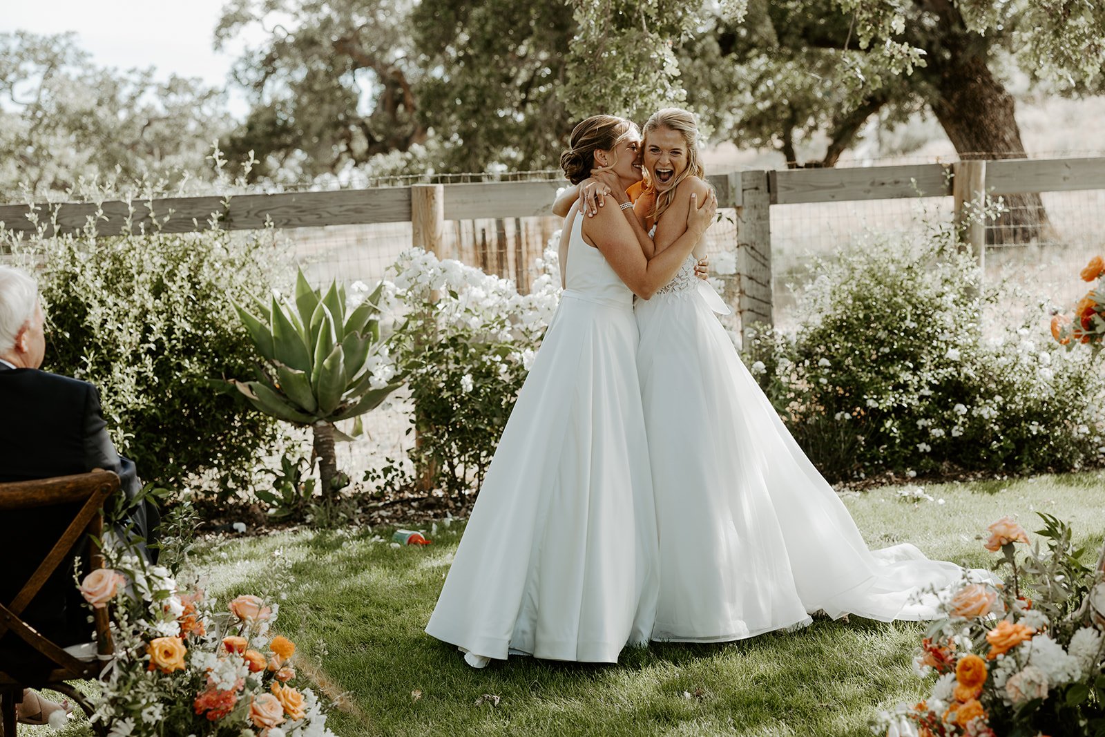 A bride kissing her wife on the cheek during a wedding ceremony