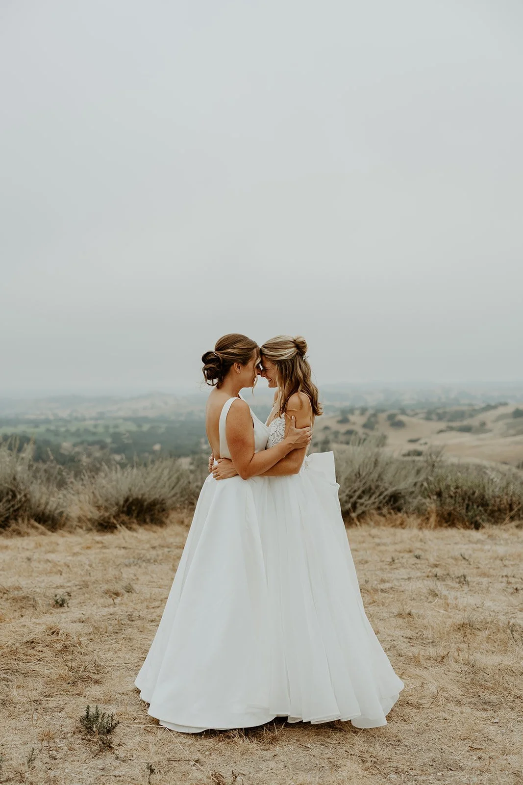 Two brides touching foreheads during wedding photos