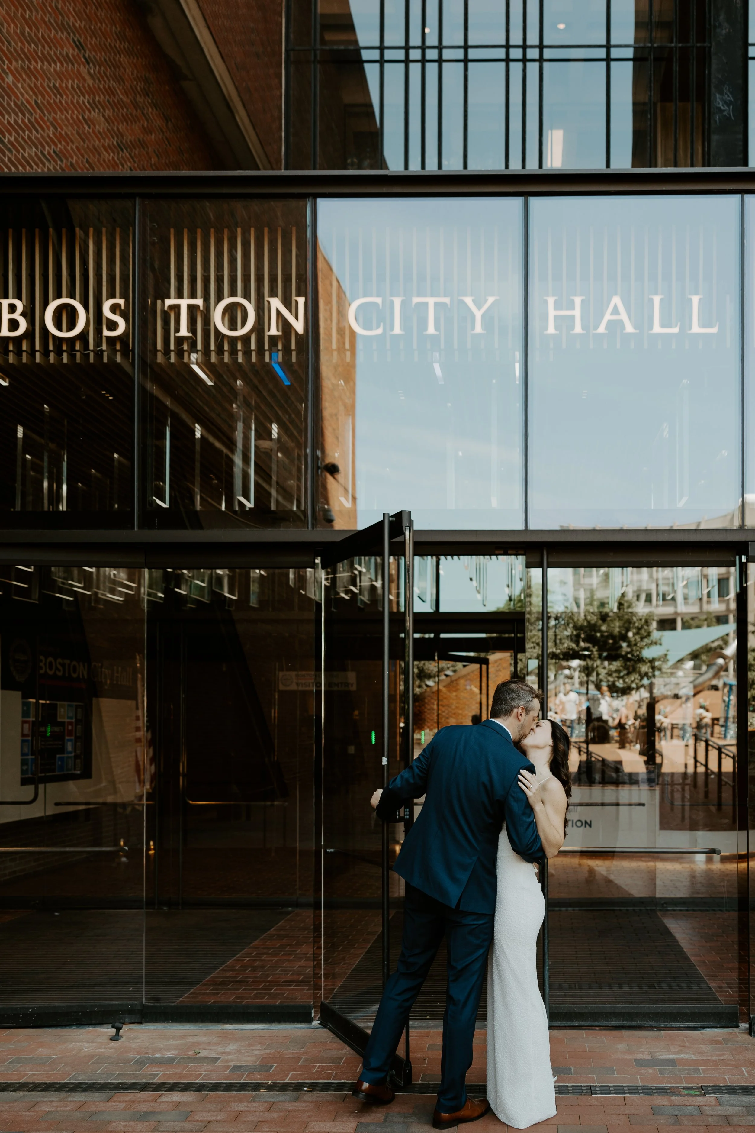 A couple kissing while walking into their elopement location, Boston City Hall