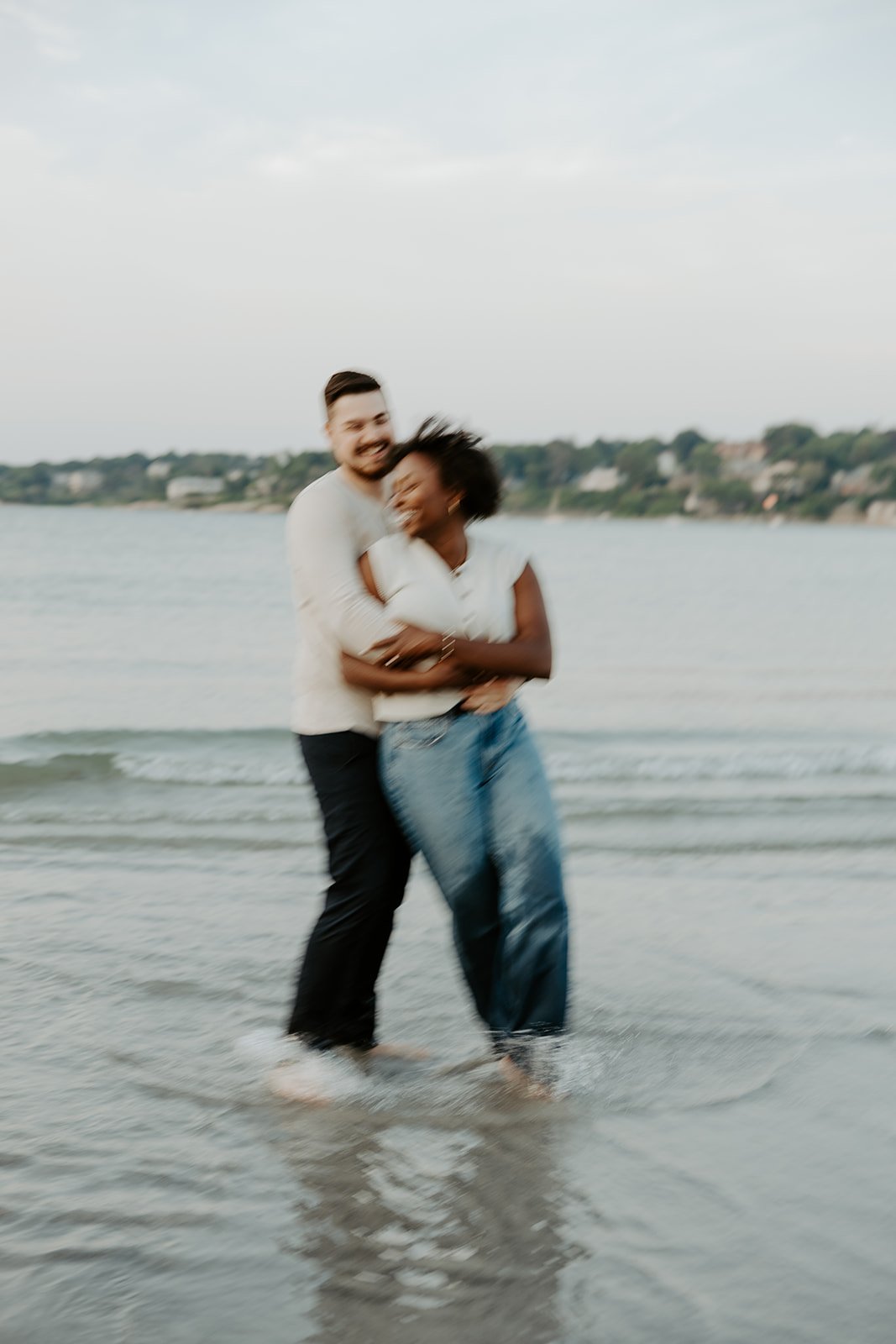 A couple laughing during their beach engagement photoshoot