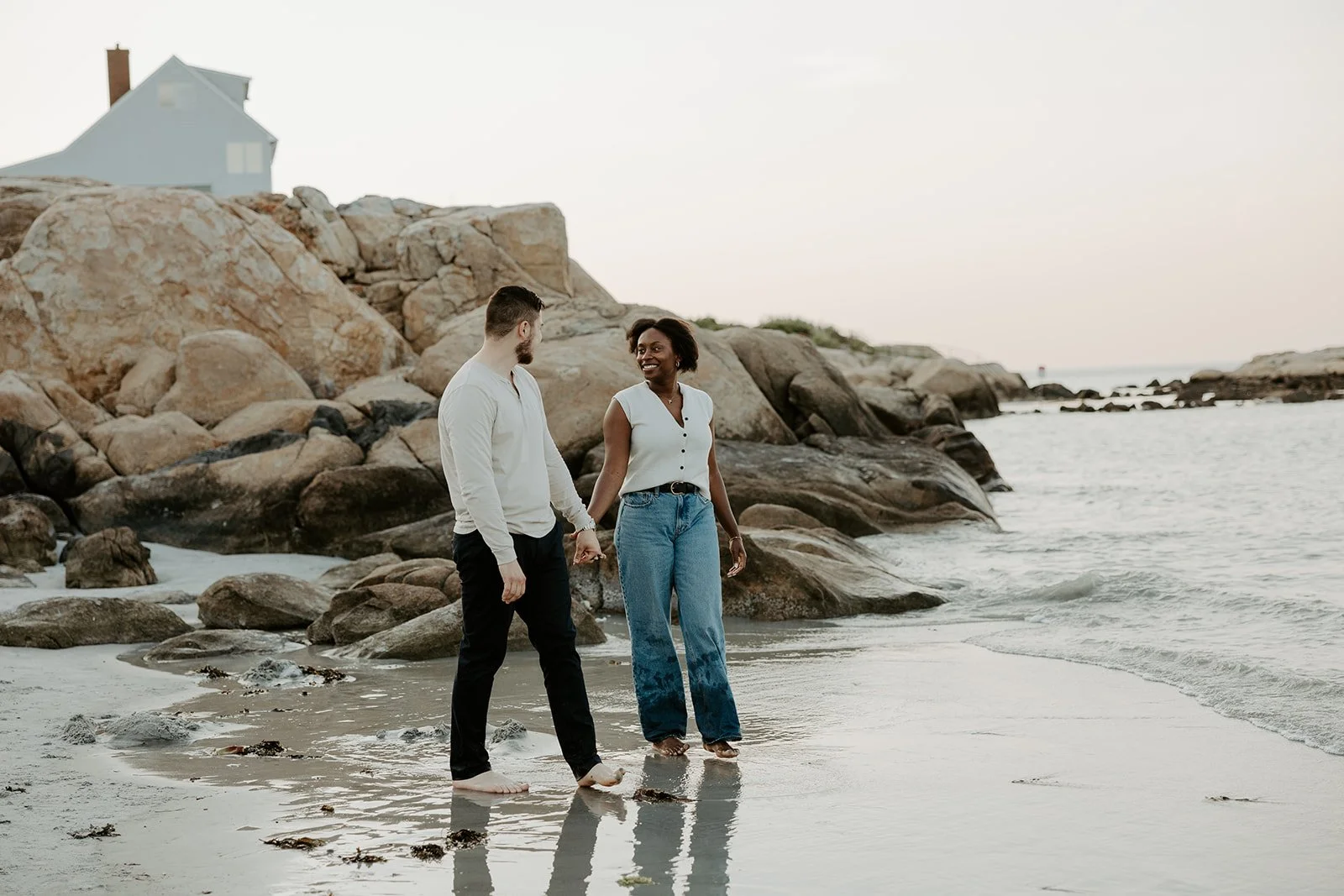 A couple holding hands on the sand on Wingaersheek beach during their beach engagement photoshoot