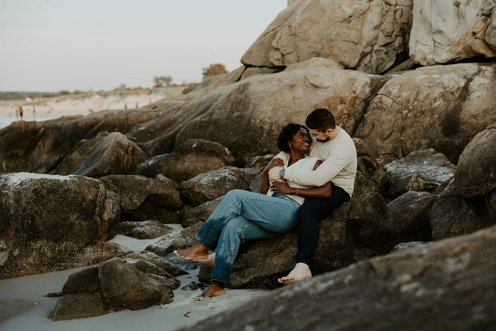 A couple sitting on therocks at Wingaersheek beach for their beach engagement photoshoot