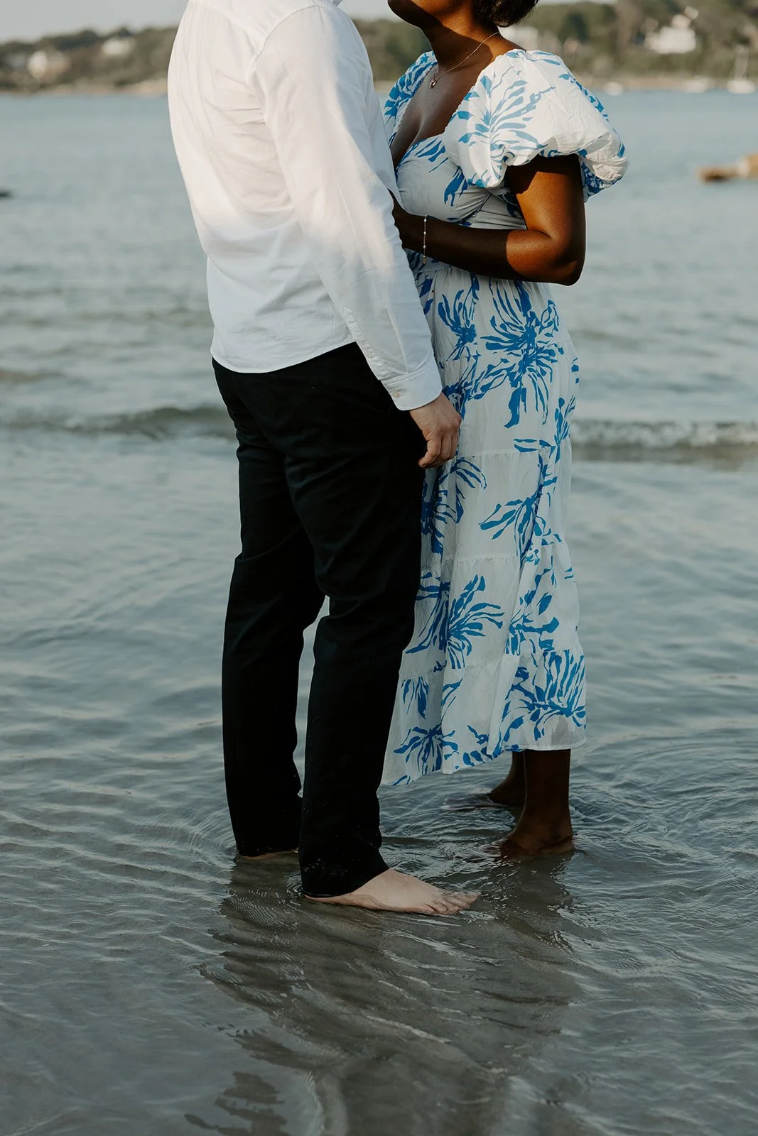 A couple standing in their beach engagement photoshoot outfits
