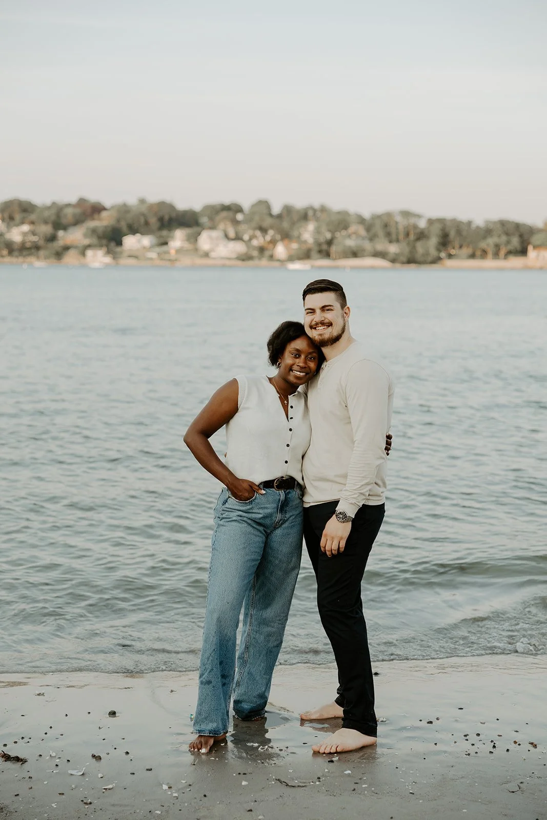 A couple posing for beach engagement photos on the shoreline at Wingaersheek beach