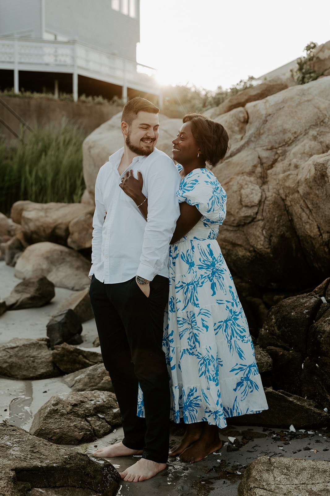 A couple smiling at each other during their beach engagement photoshoot