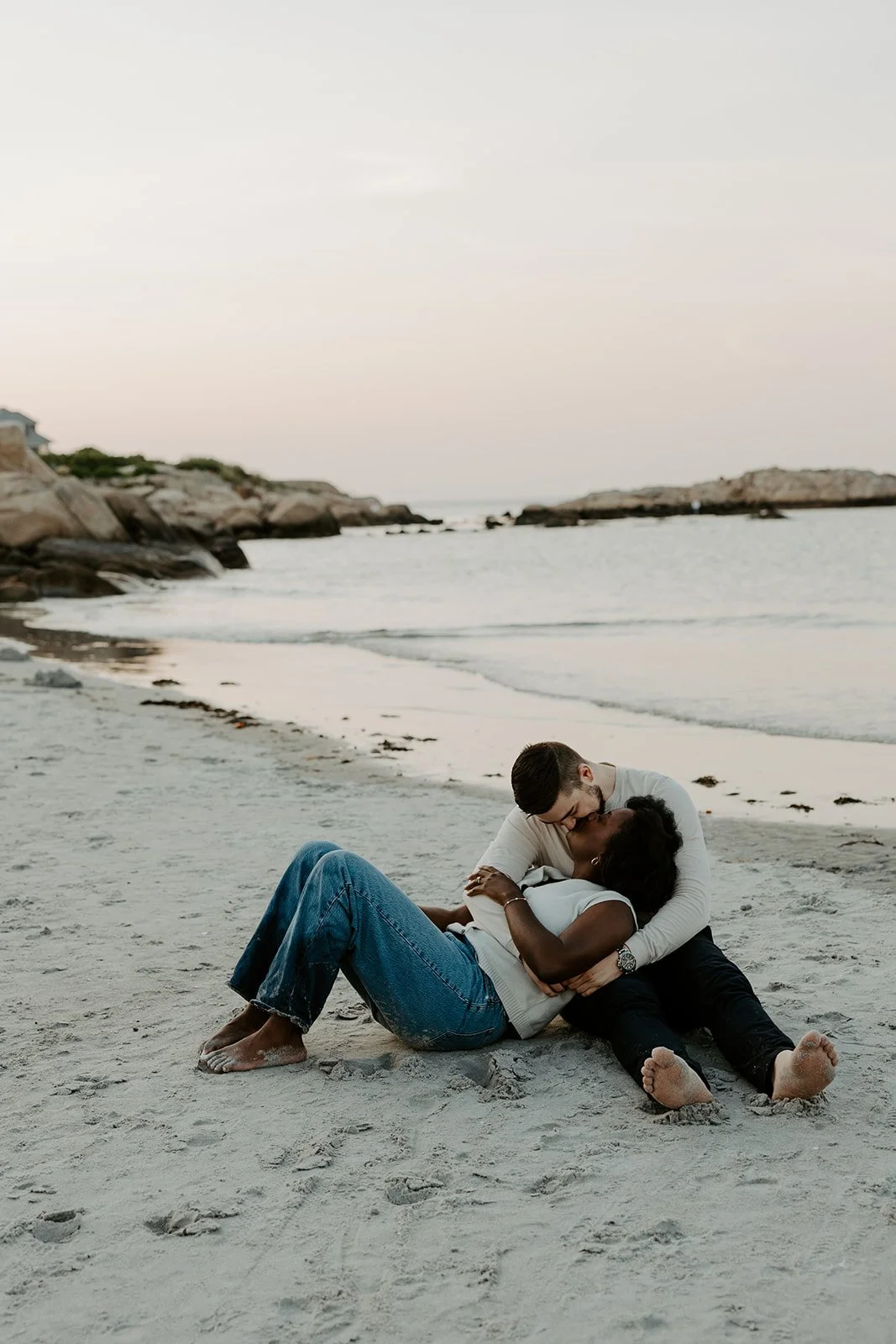 A couple ksising while laying in the sand during beach engagement photos