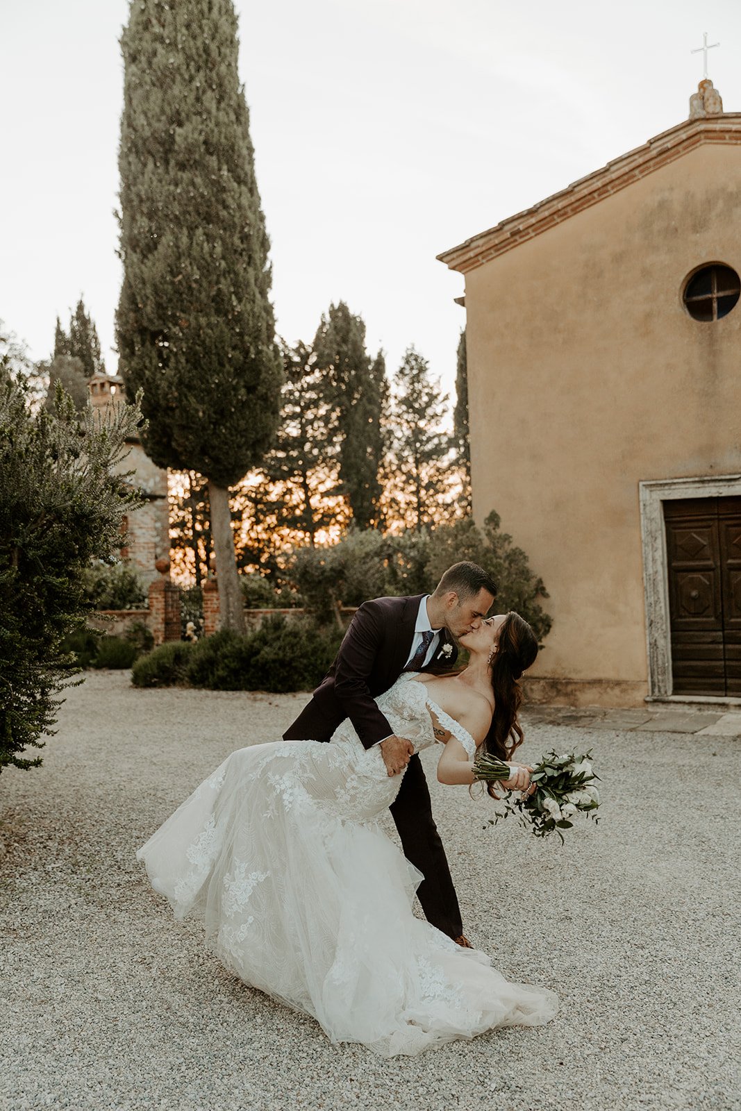 A wedding couple kissing in front of an italian villa
