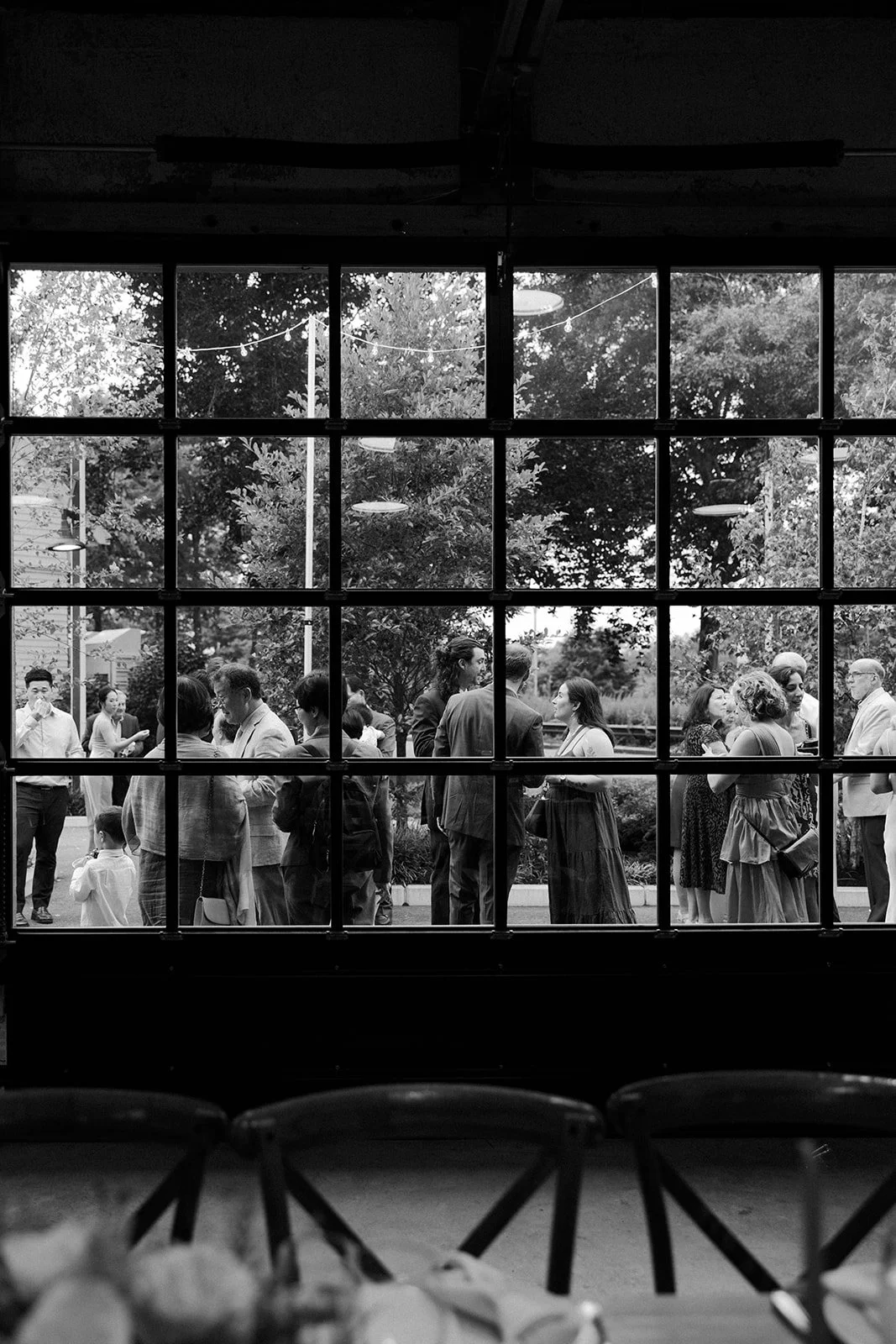 Wedding guests at a cocktail hour, in a photo taken by a Boston wedding photographer through a garage window
