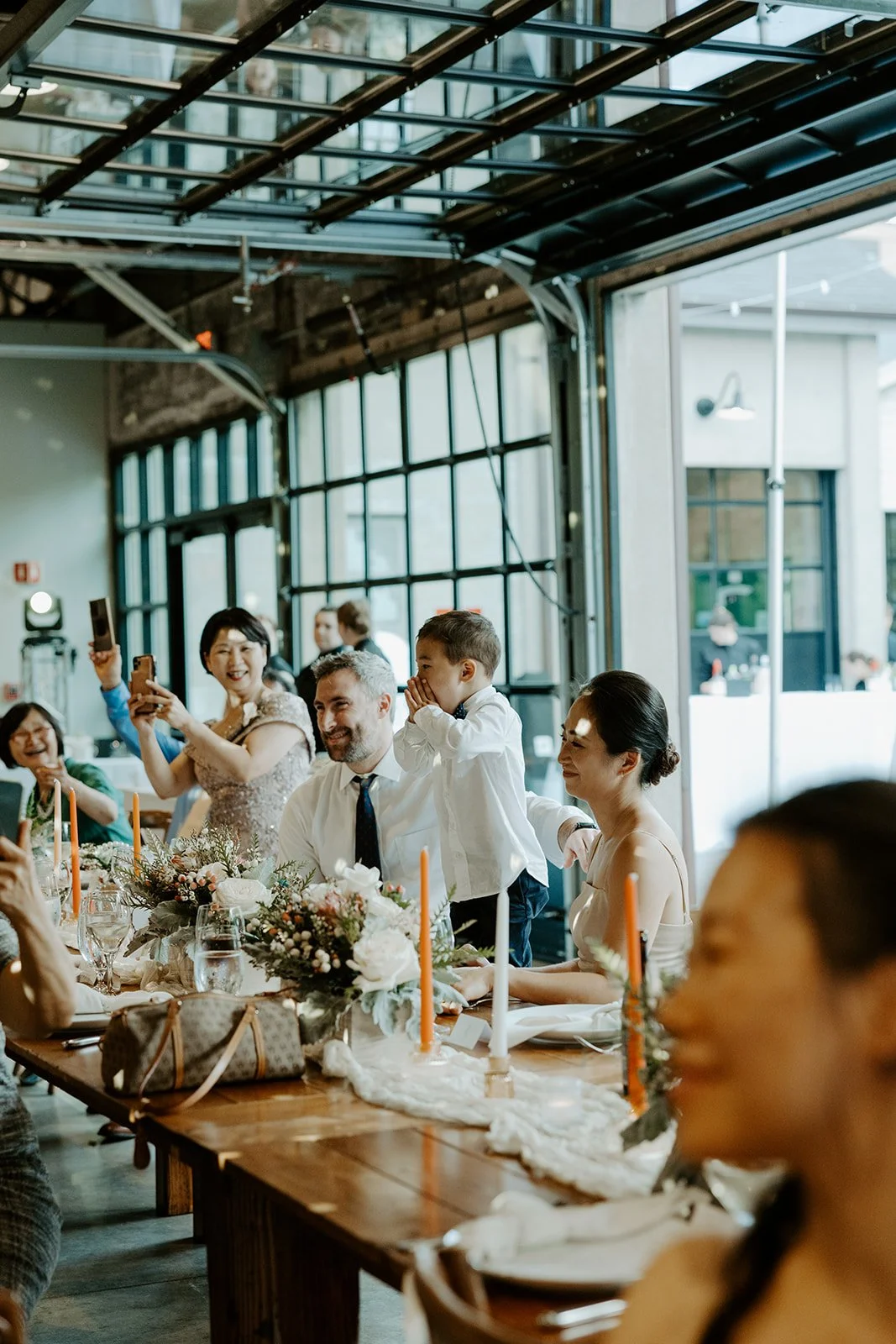 A young boy cheering for the bride and groom dancing at a garage b wedding reception