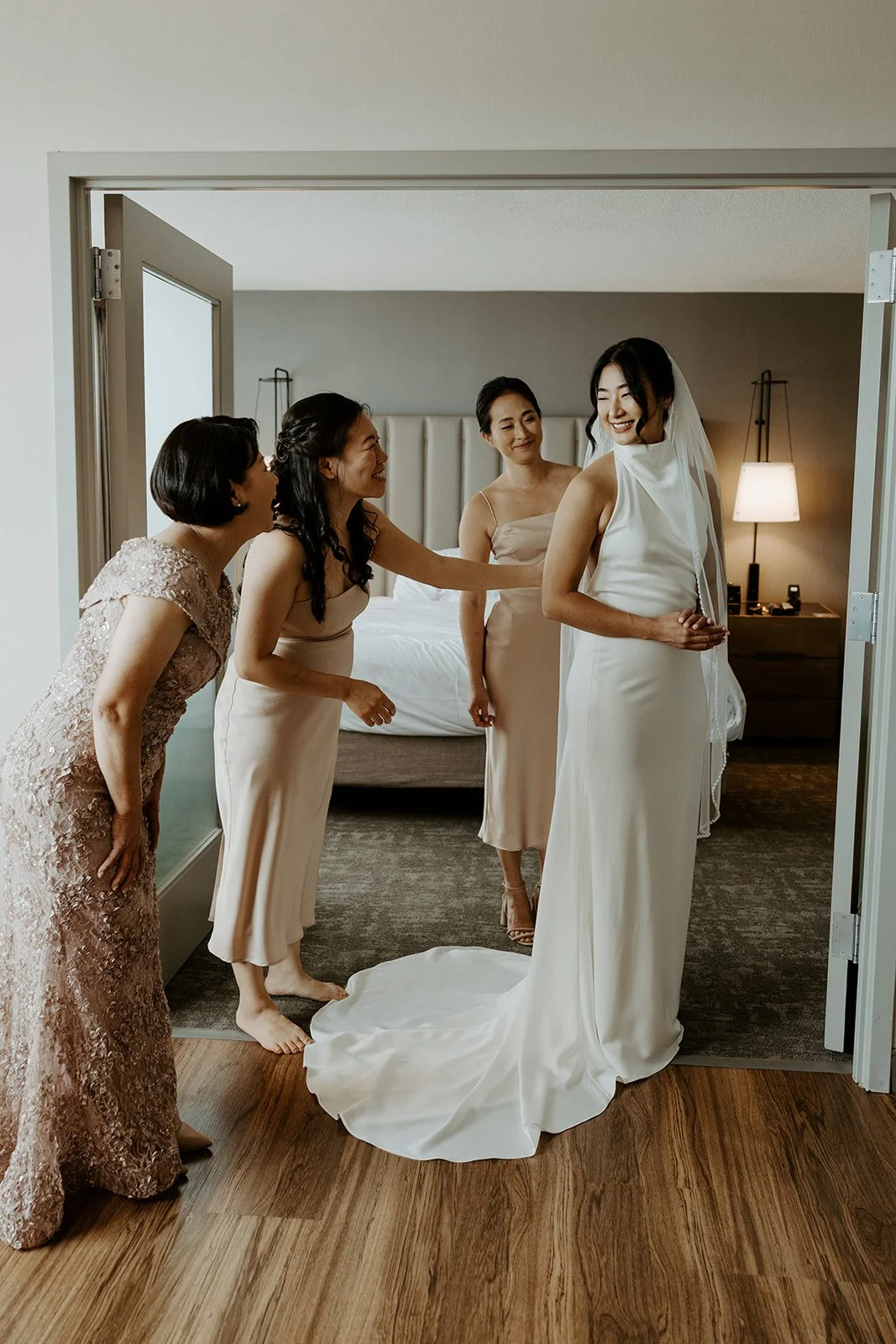 A bride's sisters and mom helping her get ready for her wedding