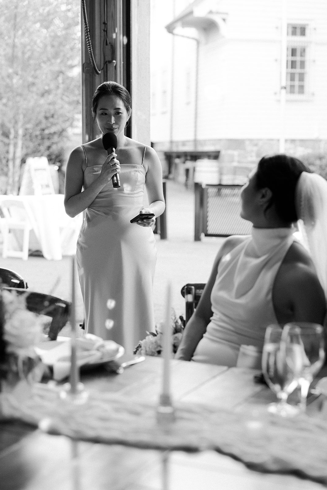 A bride watching her sister give a toast at her wedding reception
