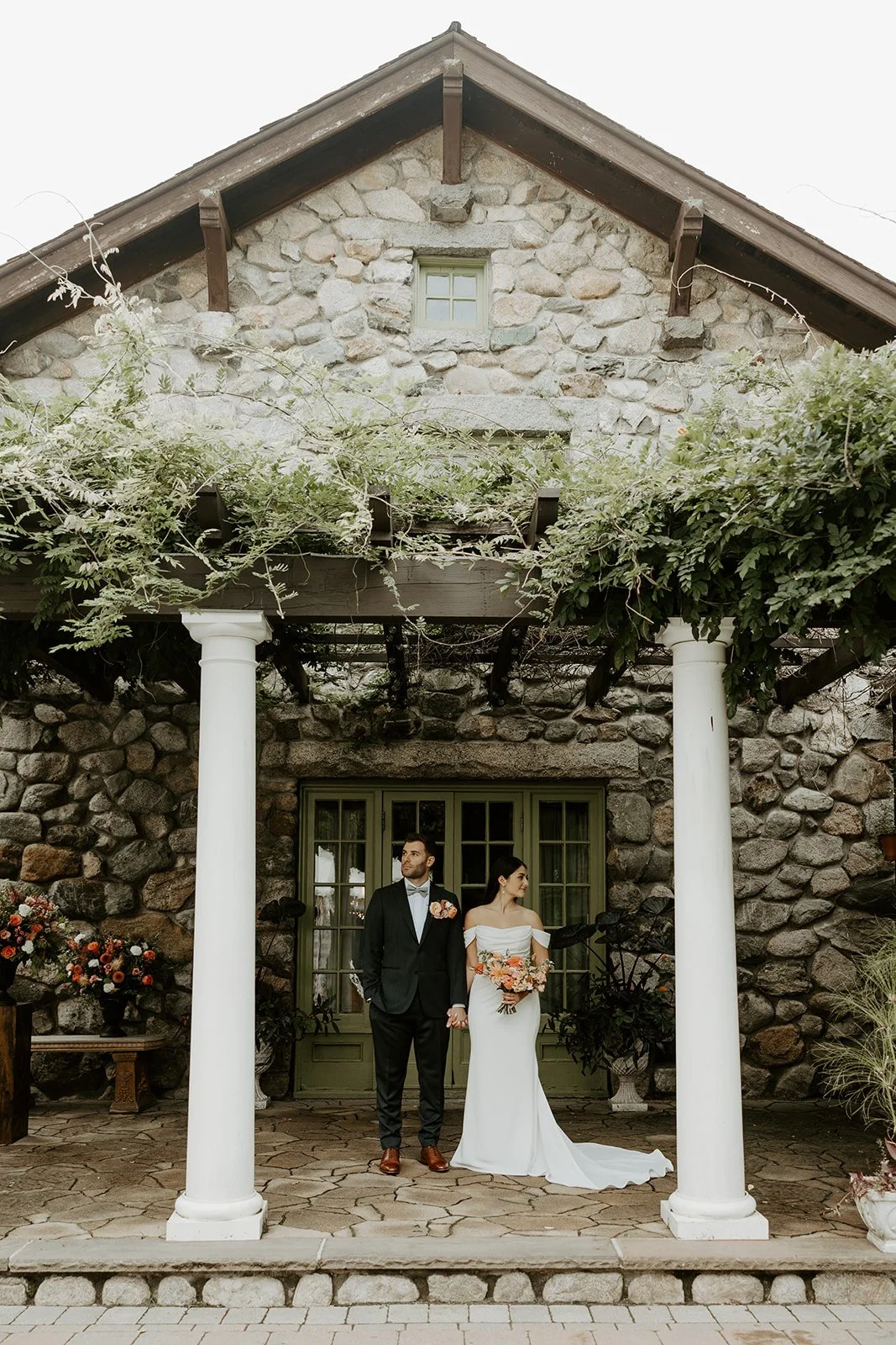 A couple posing for wedding photos in front of their Massachusetts wedding venue