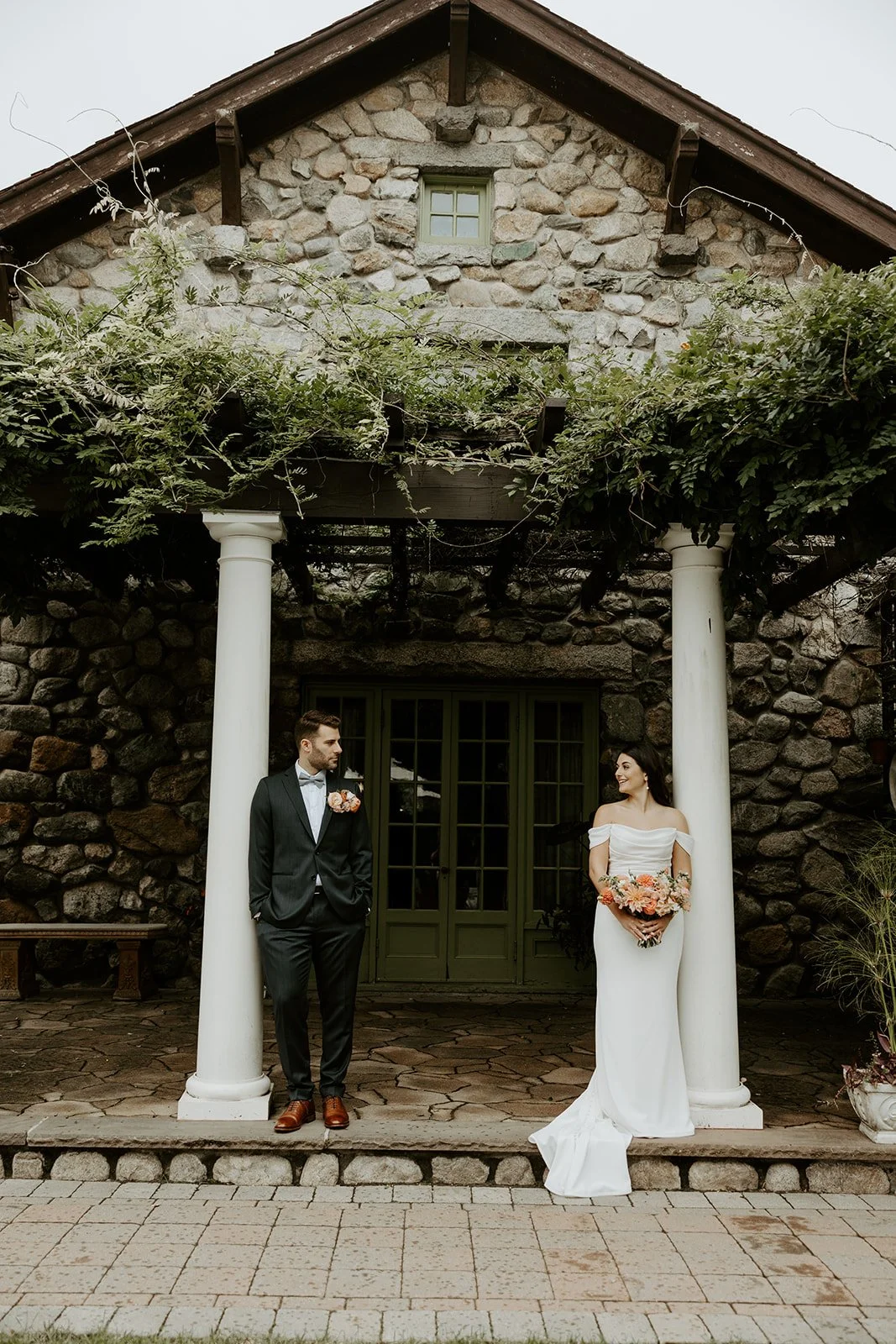 A couple posing for wedding photos in front of their Massachusetts wedding venue