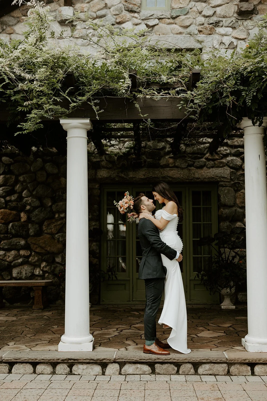 A couple posing for wedding photos in front of their Massachusetts wedding venue