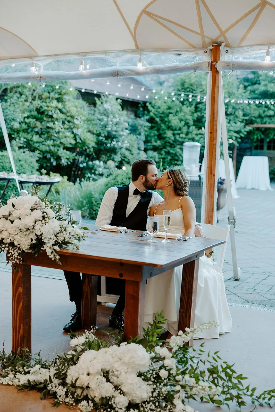 A bride and groom kissing at their sweetheart table