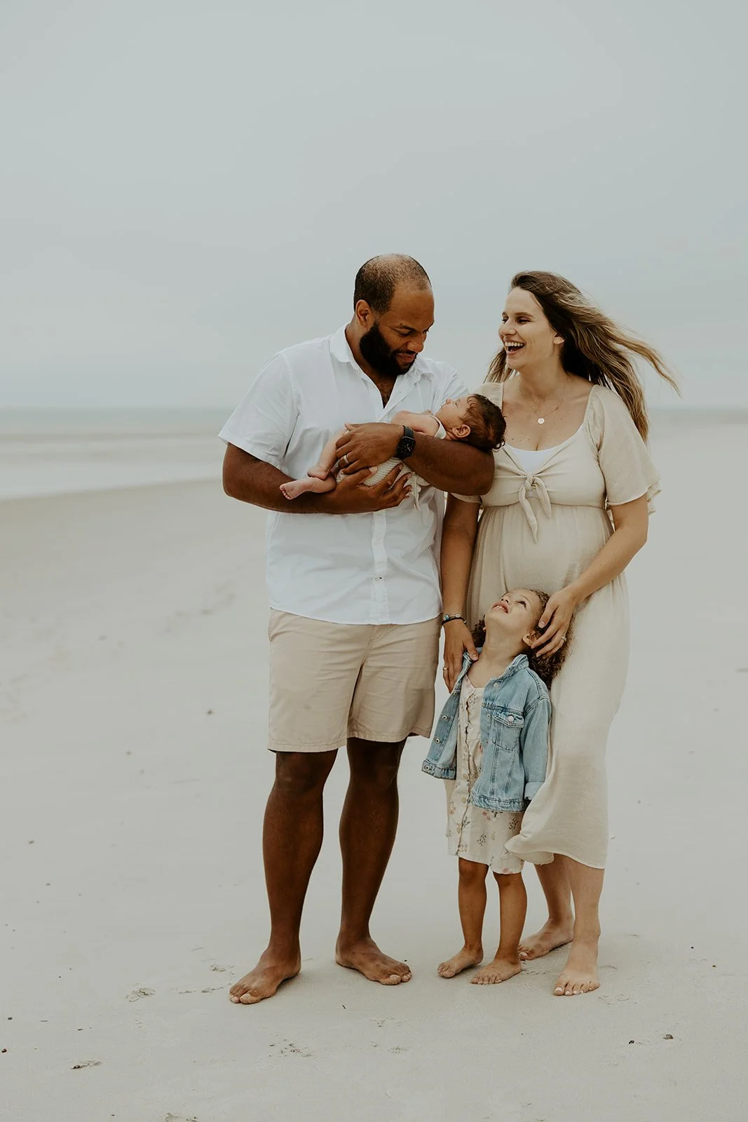 A family posing for photos during a beach family photoshoot