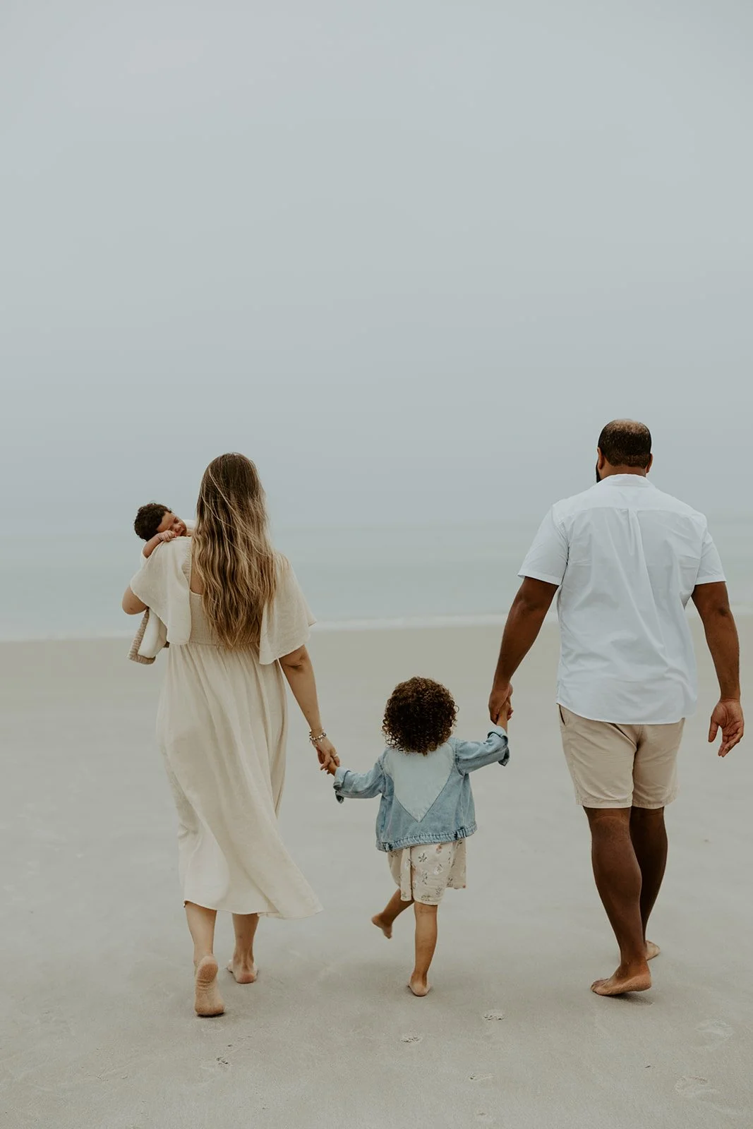 A family holding hands walking on the beach during a beach family photoshoot