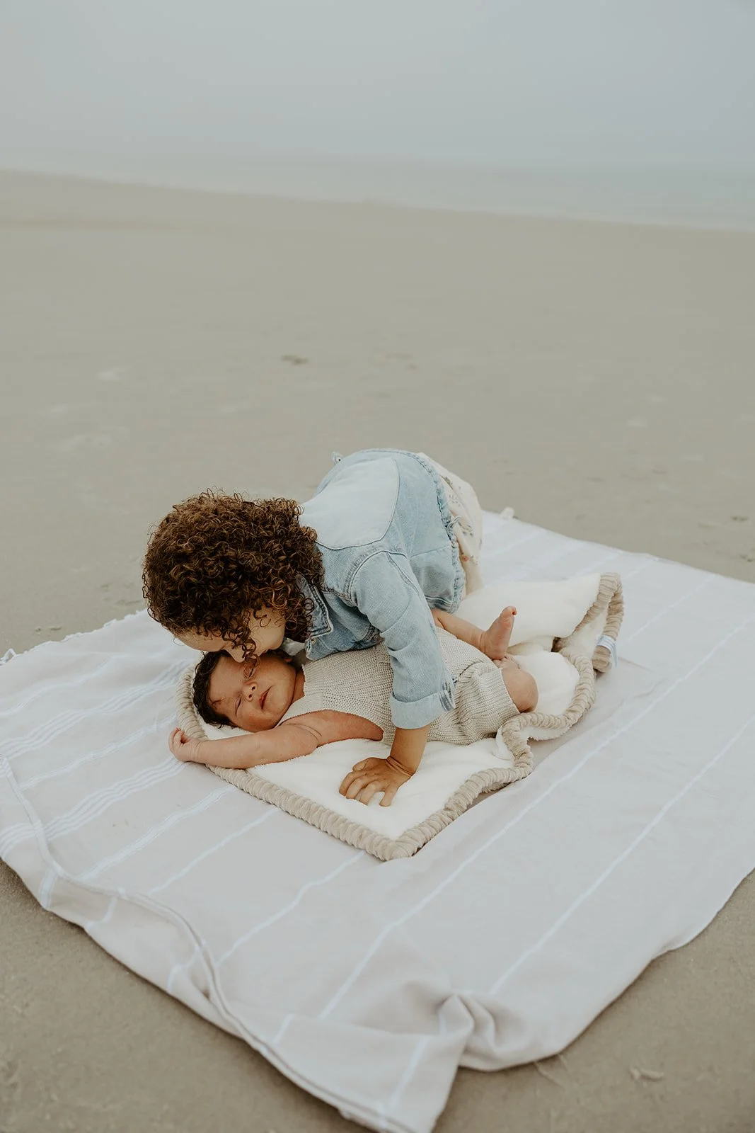 A little girl kissing her baby brother during a beach family photoshoot