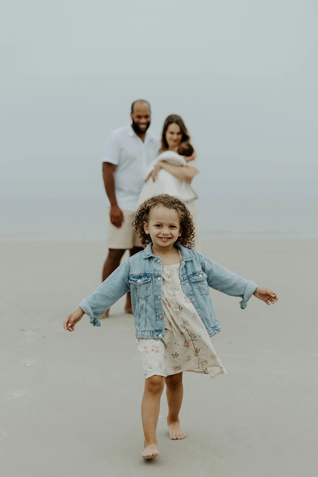 A little girl running in front of her family during a beach family photoshoot
