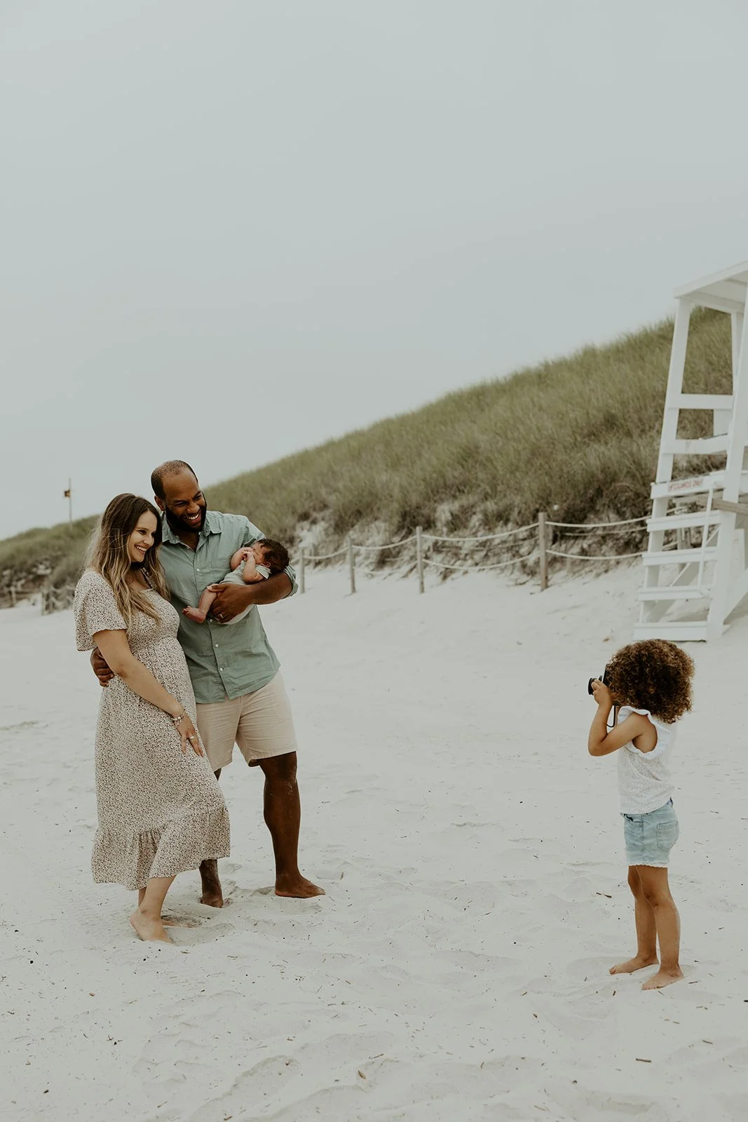 A young girl taking pictures of her family on the beach
