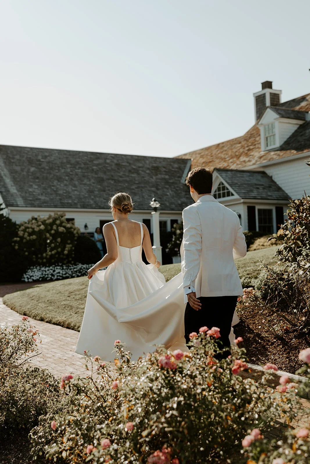 A bride and groom walking away from the camera at their cape cod wedding venue