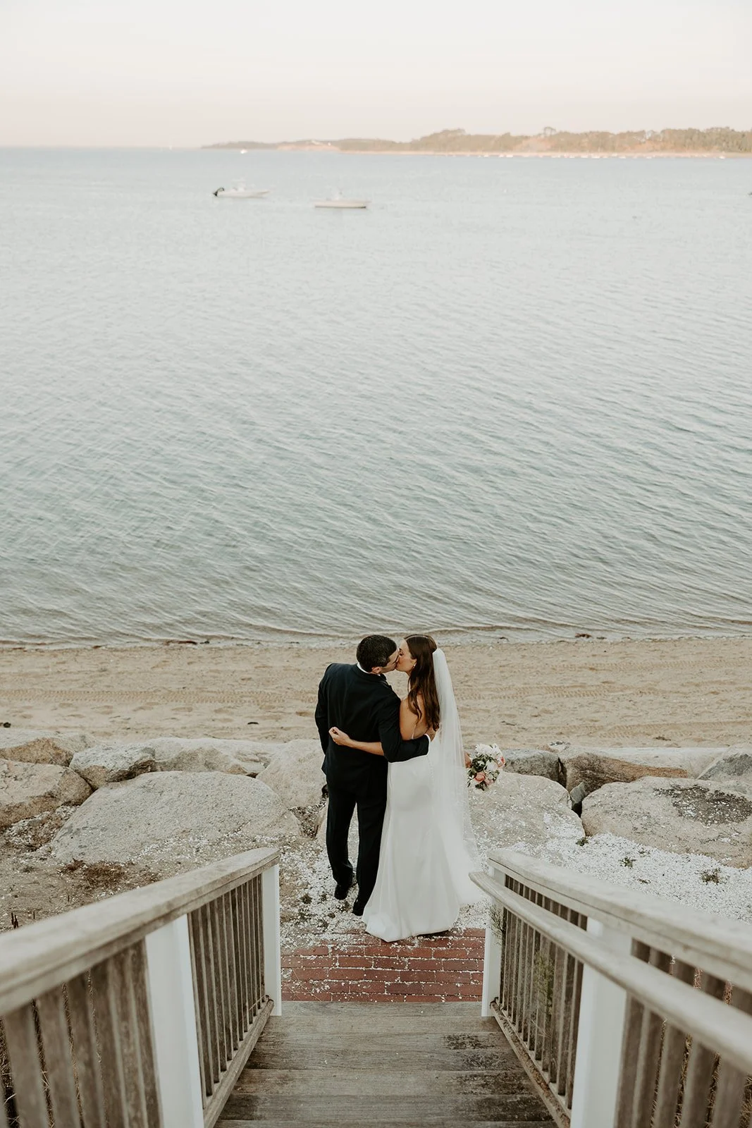 A bride and groom walking towards the beach at their cape cod wedding venue