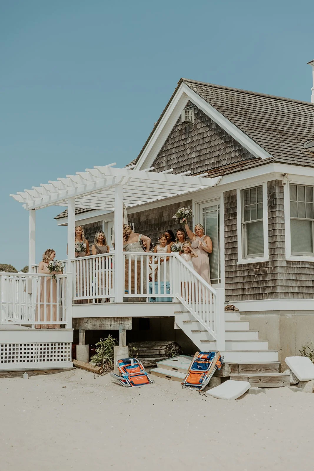 Bridesmaids cheering from the porch of the cape cod wedding venue