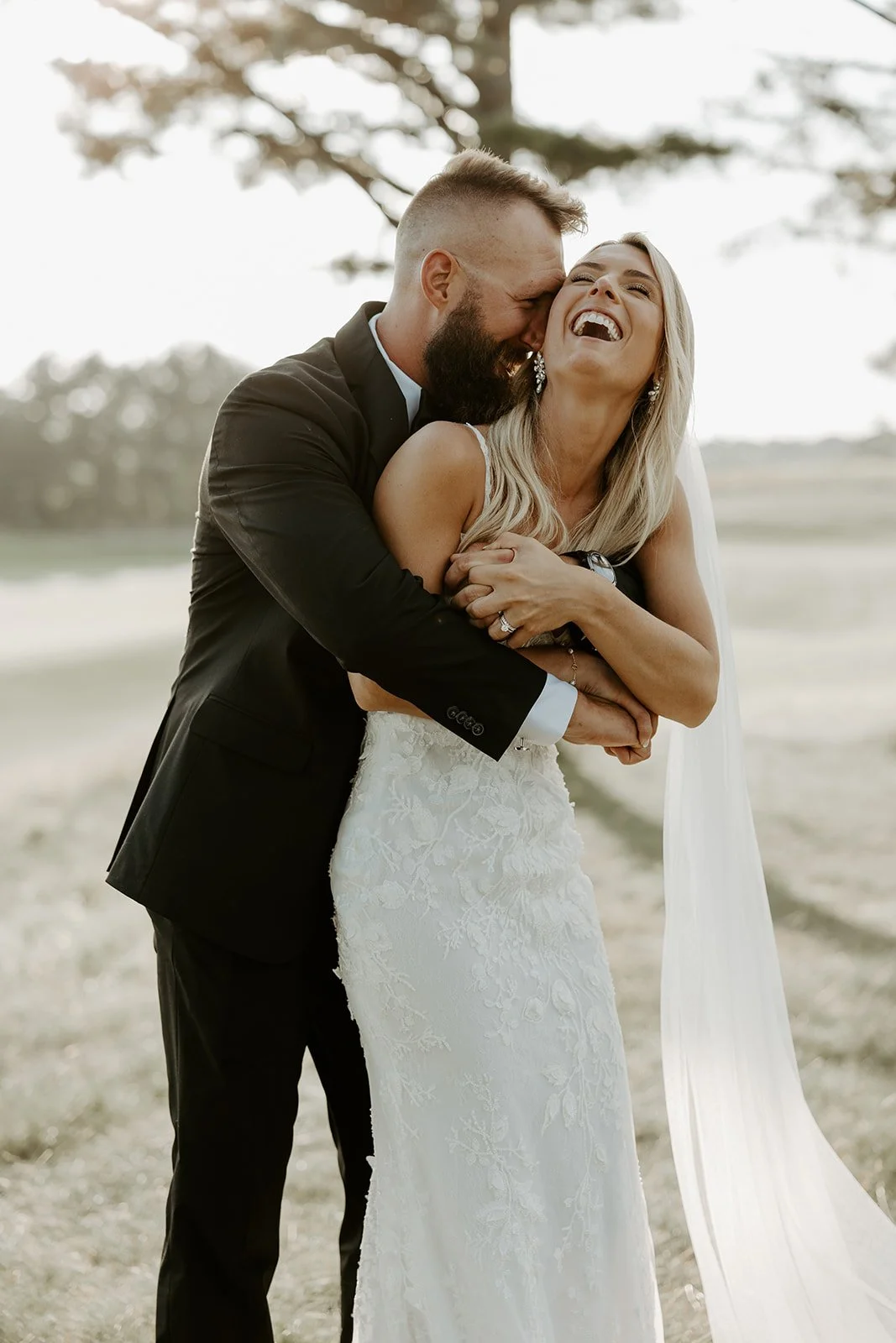 A bride and groom laughing while taking sunset photos