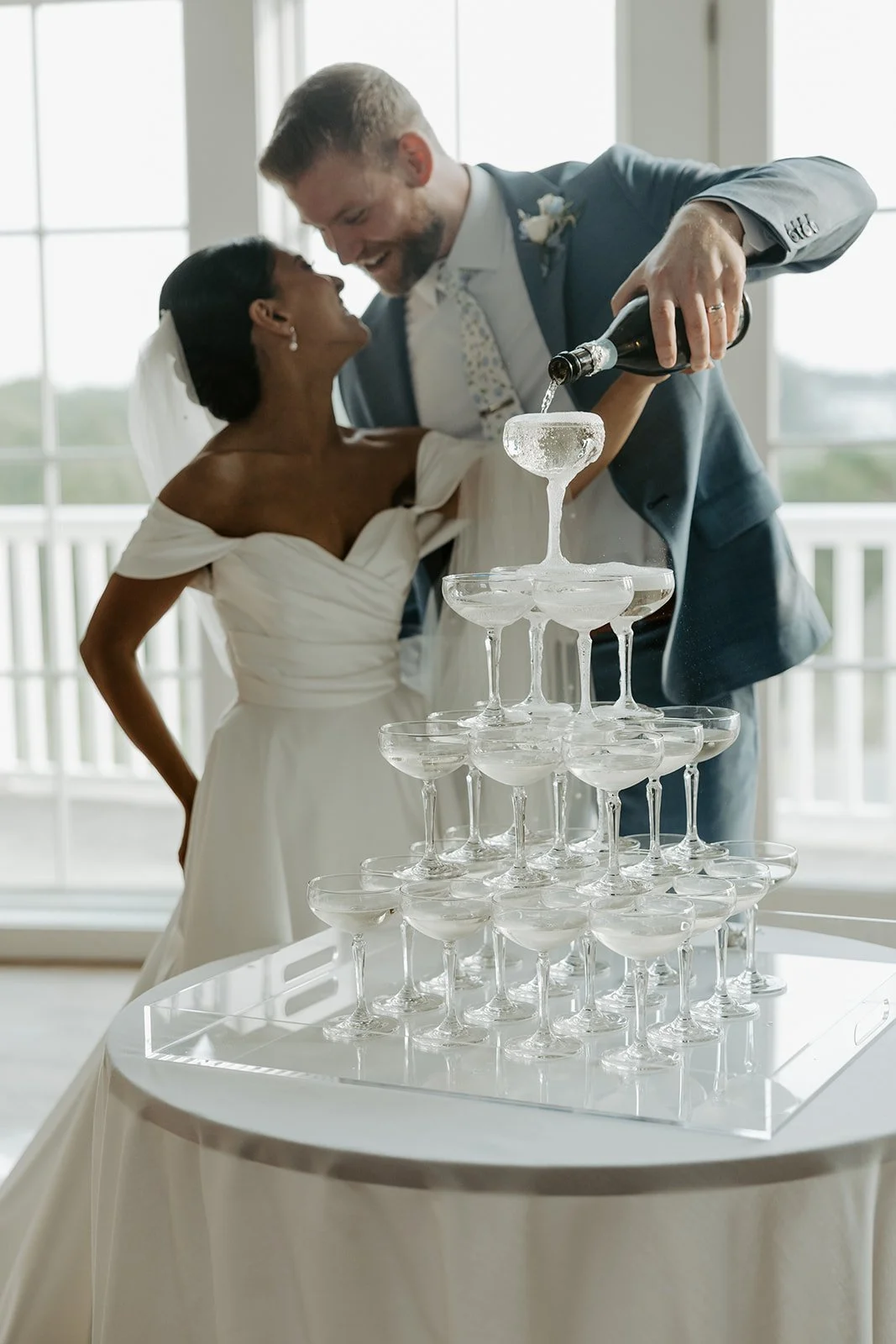 A bride and groom pouring champagne into a wedding champagne tower