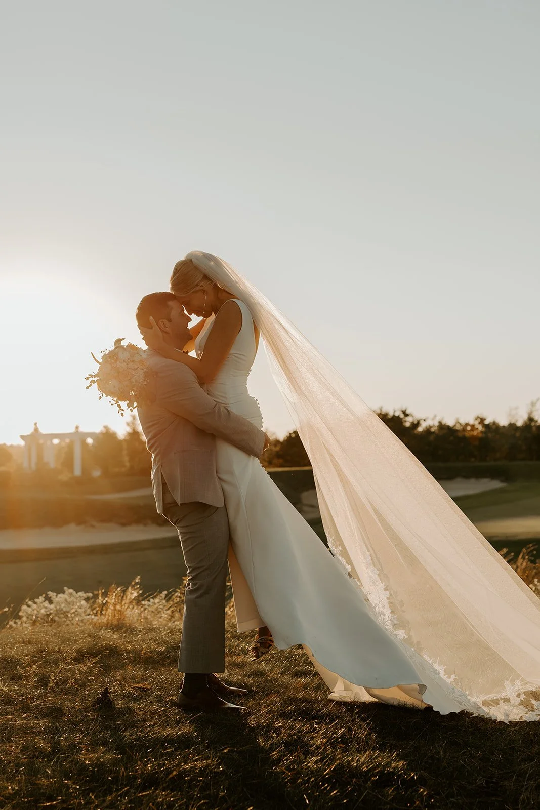 A bride and groom taking sunset photos at their wedding