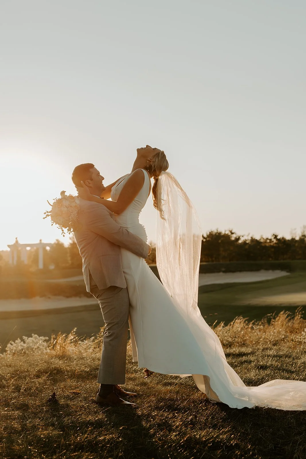 A bride and groom taking sunset photos at their wedding