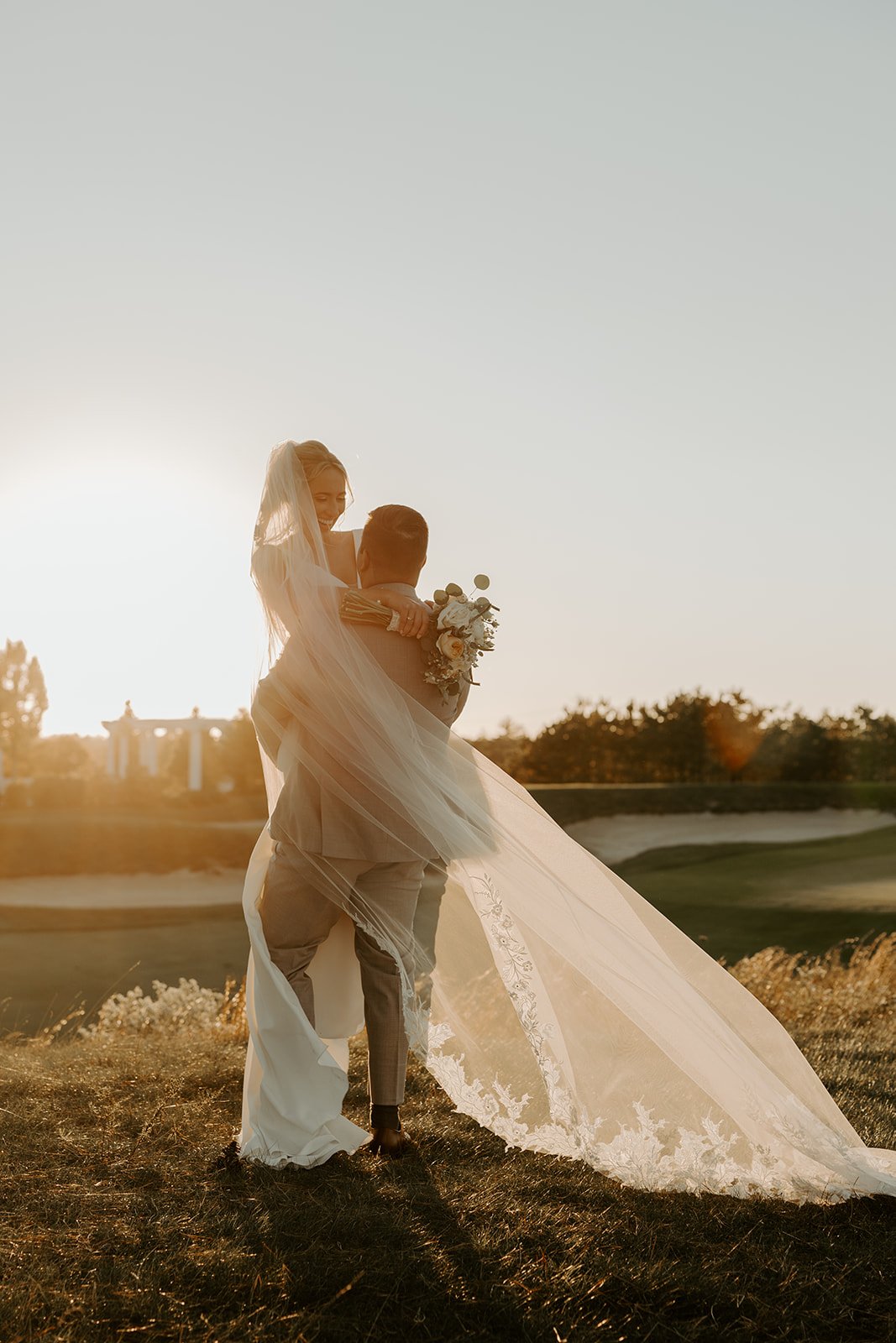 A bride and groom taking sunset photos at their wedding