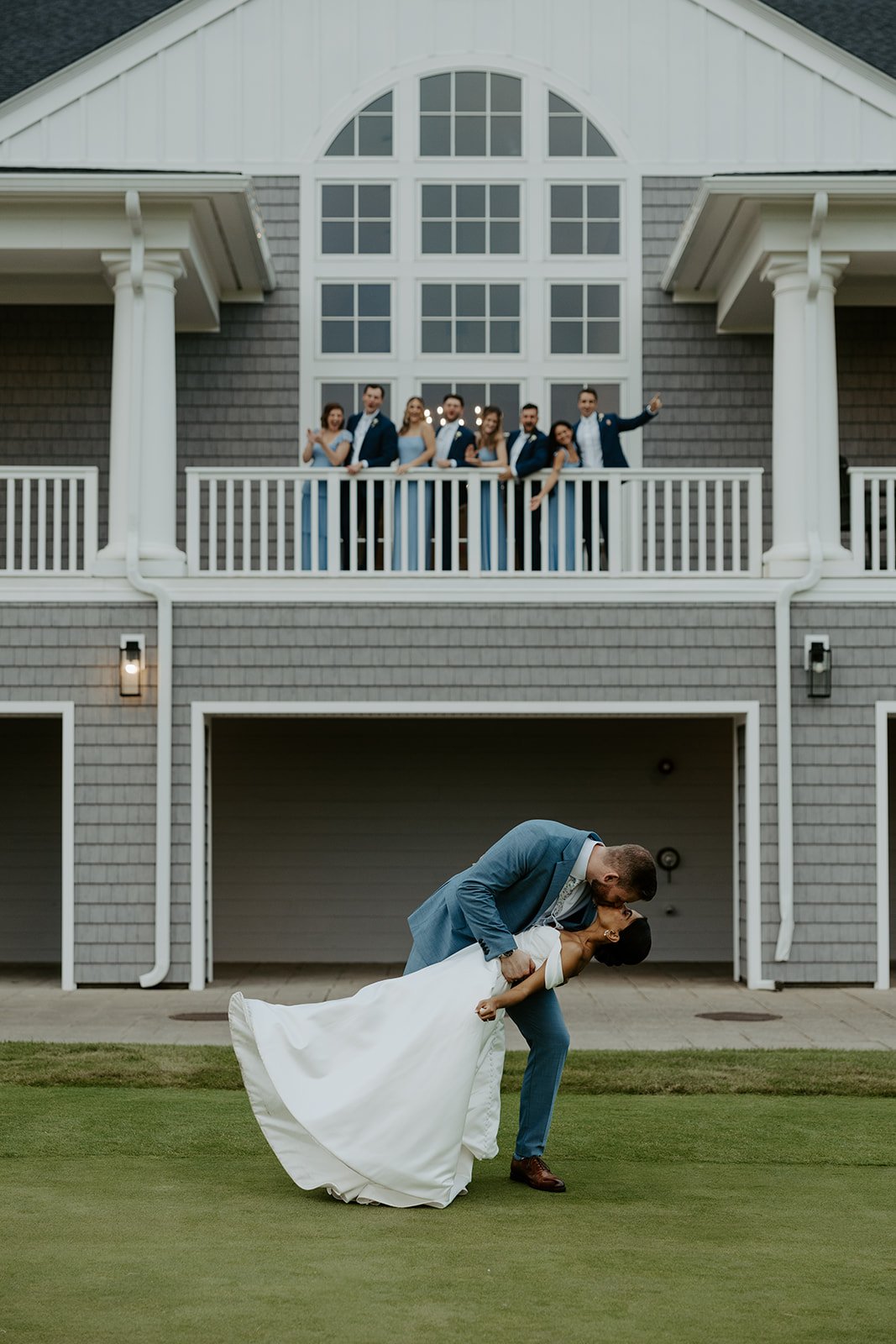 A bride and groom kissing in front of a cheering bridal party