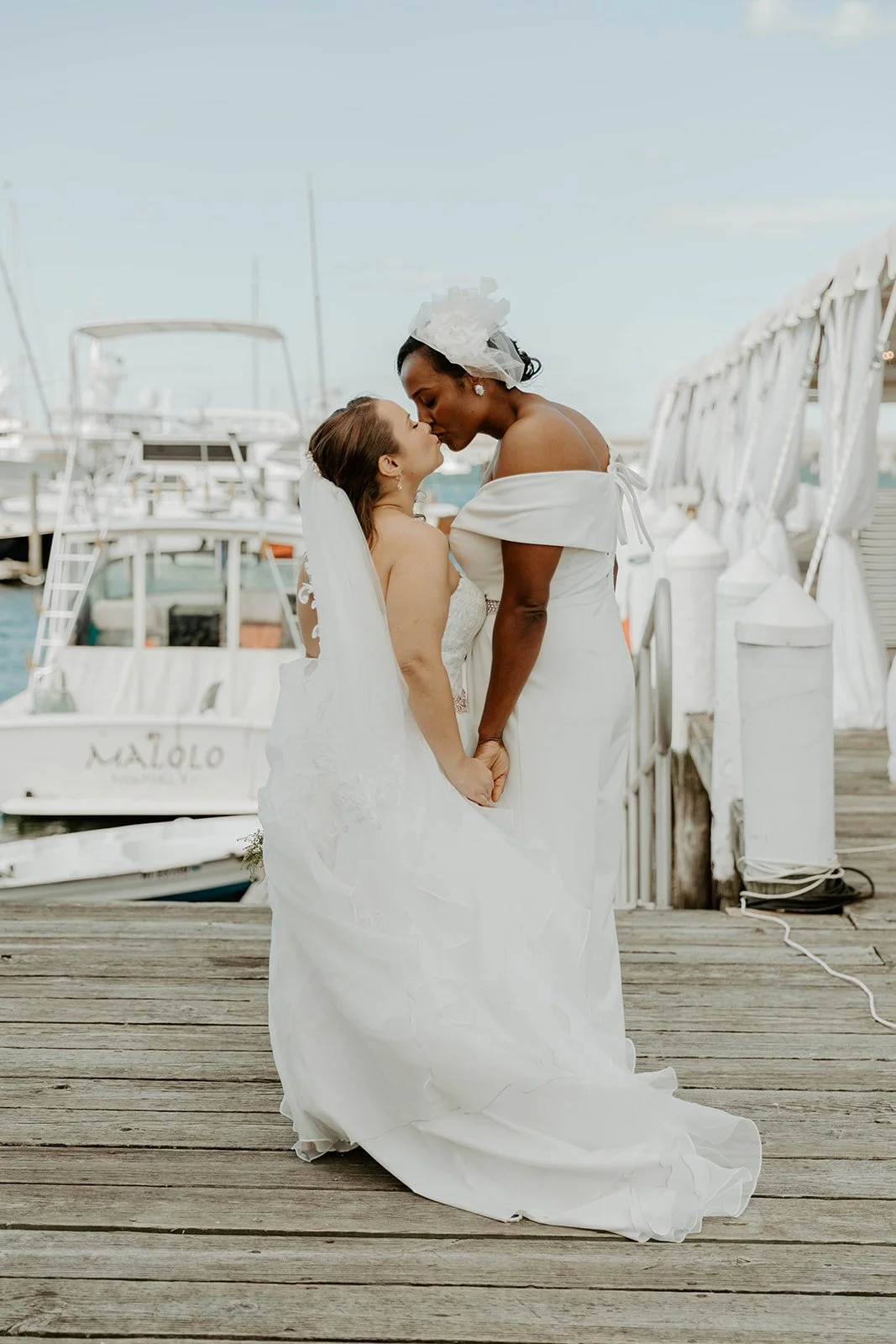 Two brides kissing on a dock at Regatta place