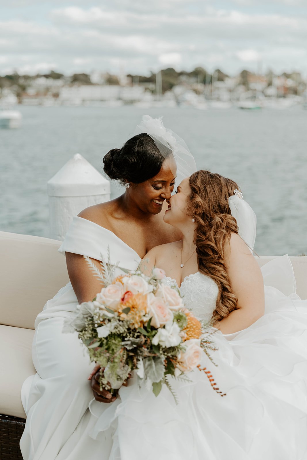 Two brides leaning in for a kiss during wedding portraits