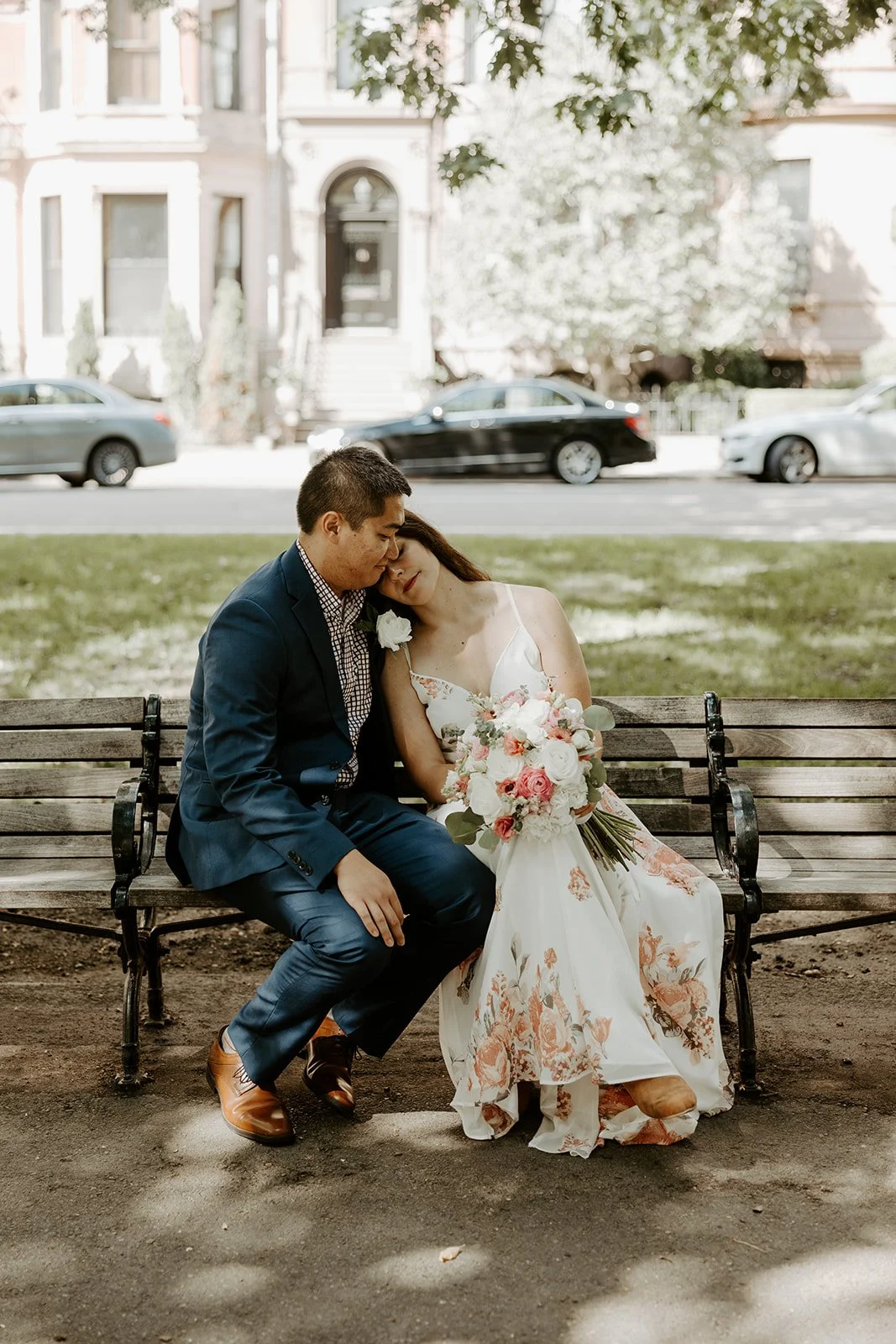 A couple posing for wedding portraits on a bench in Boston